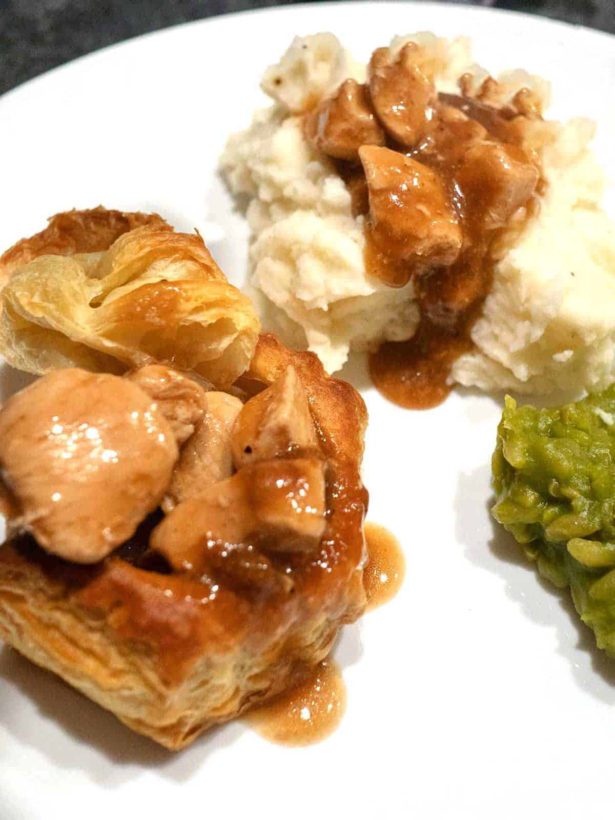 Chicken vol au vents on plate with mashed potatoes and peas.
