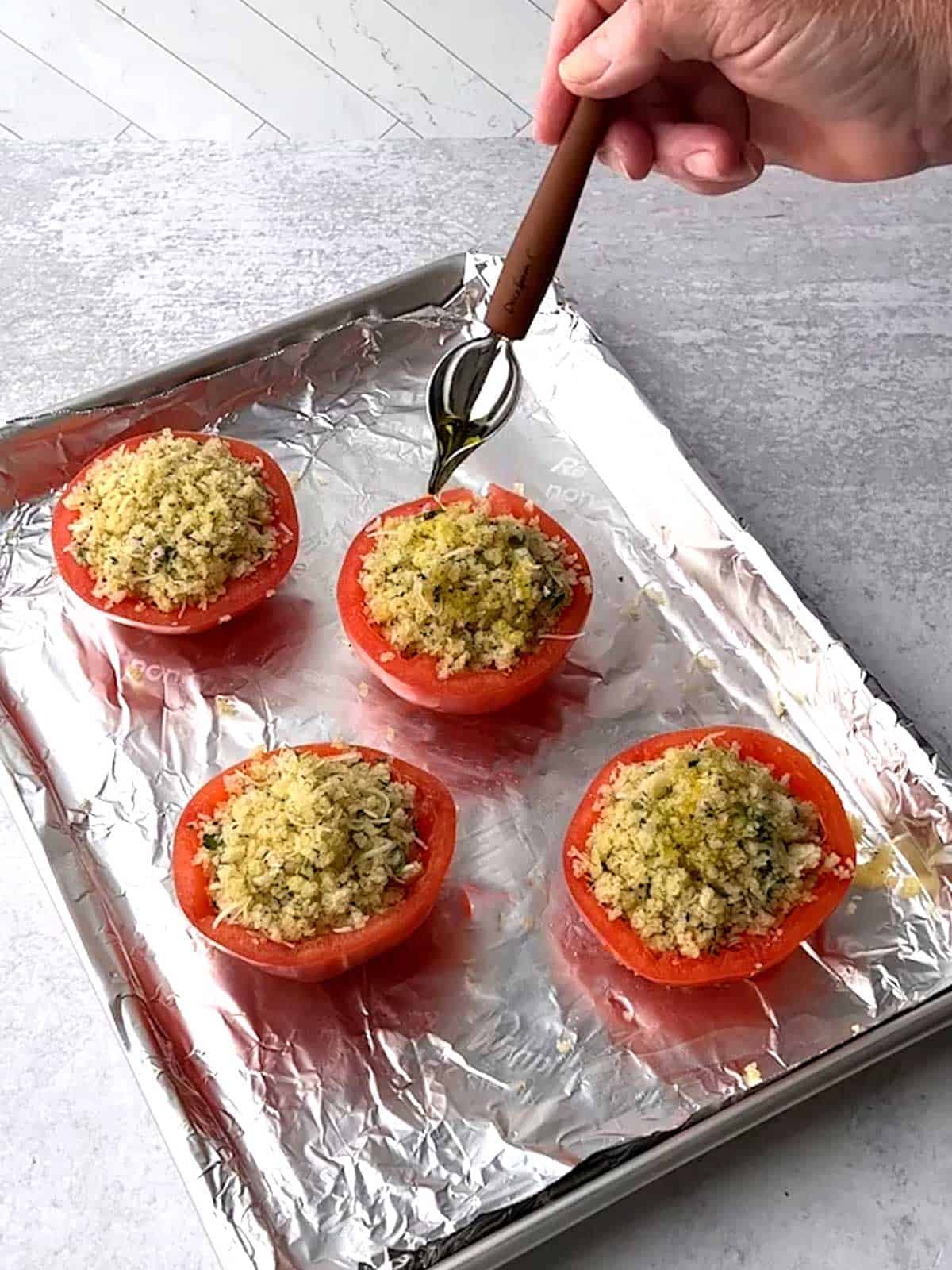 Drizzling olive oil on top of stuffed tomatoes.
