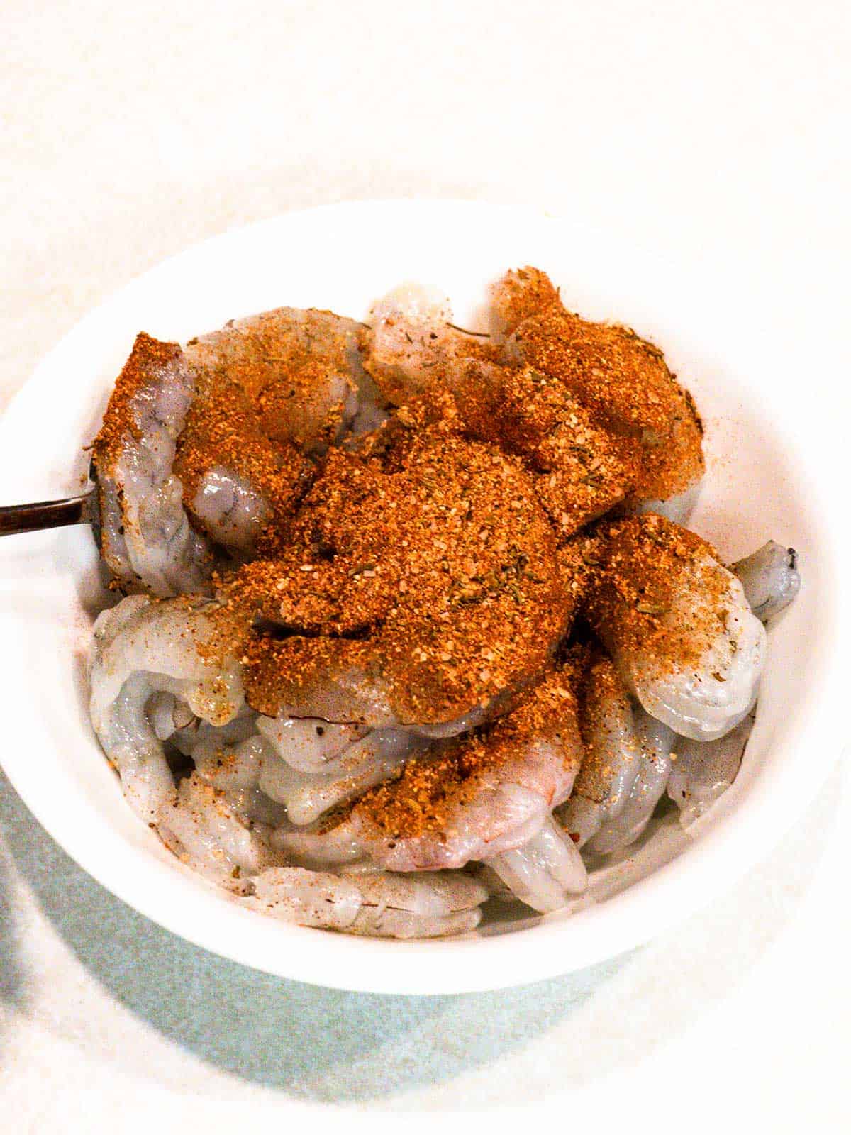 Seasoning shrimp with Creole seasoning.