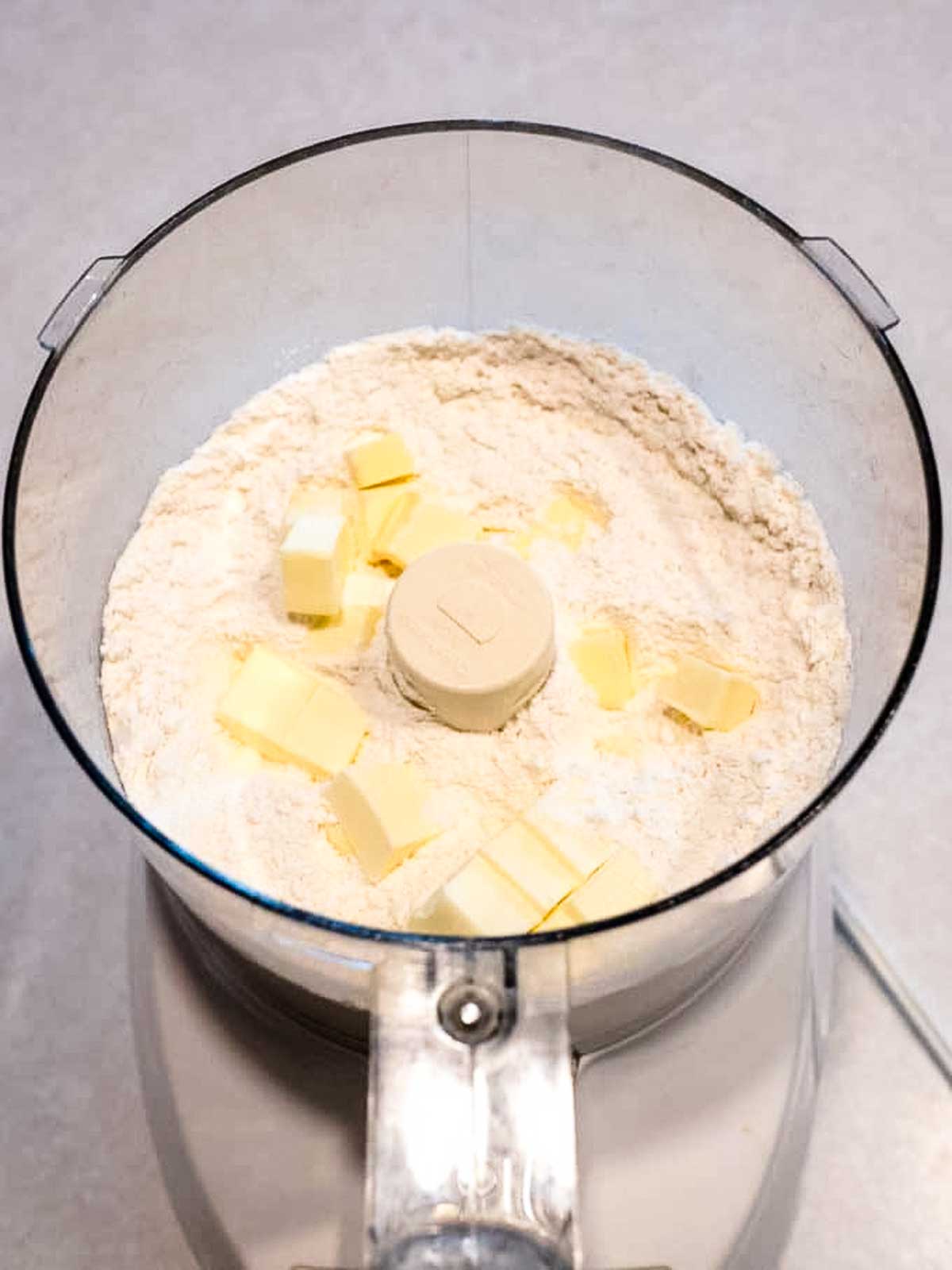 Adding butter to food processor.