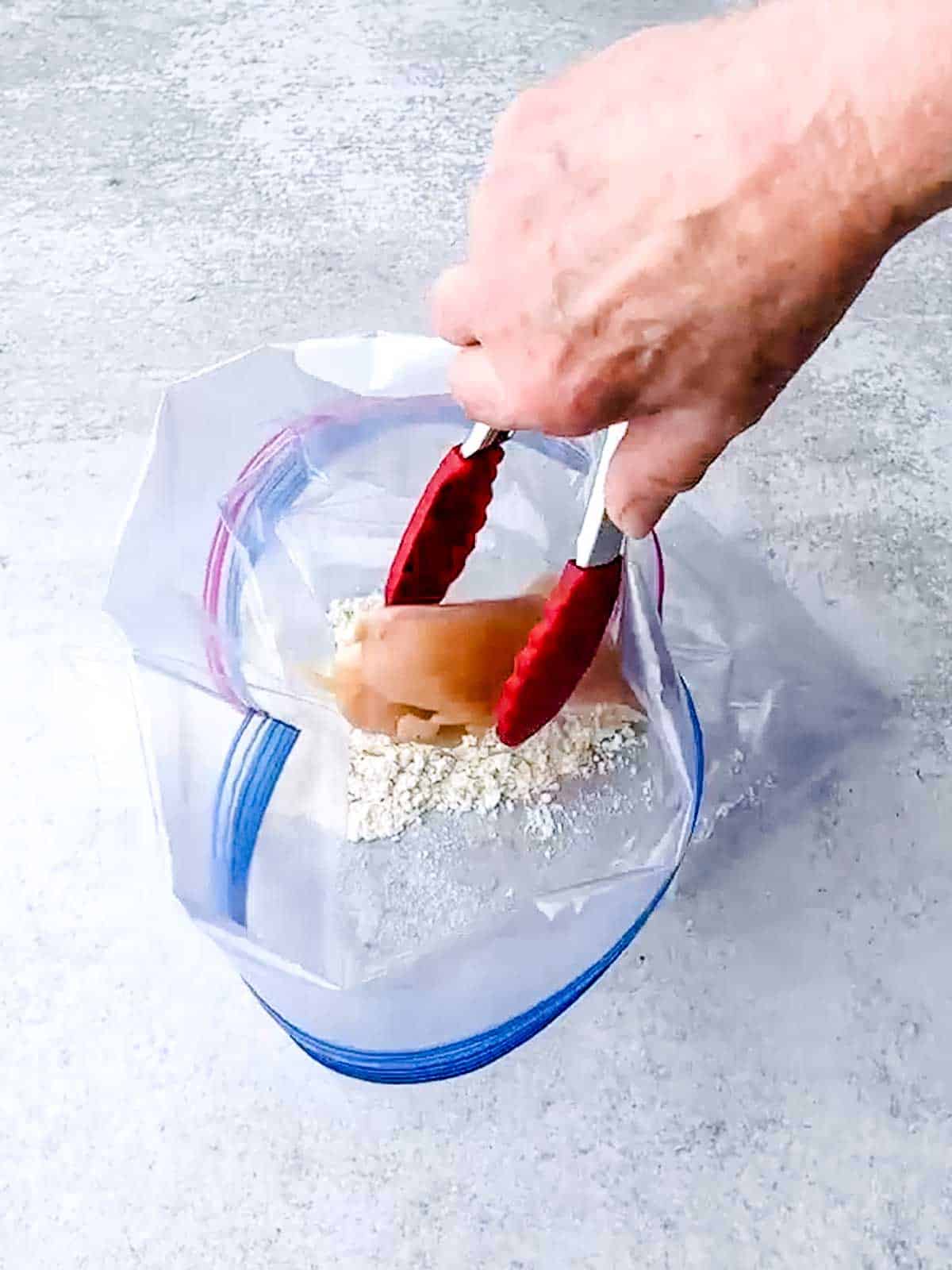 Adding chicken to Ziploc bag with flour, salt and pepper.