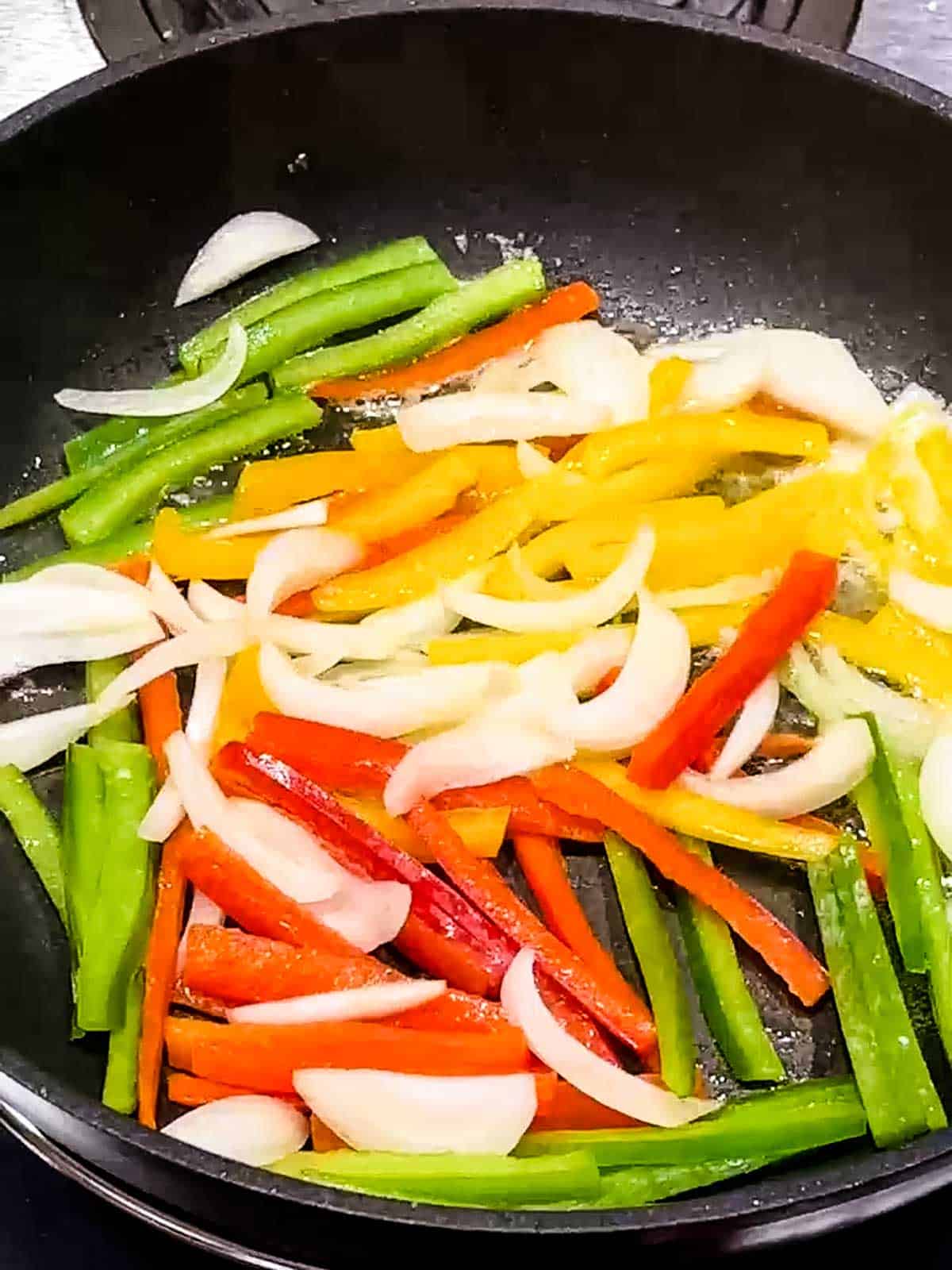 Cooking peppers and onions in skillet.