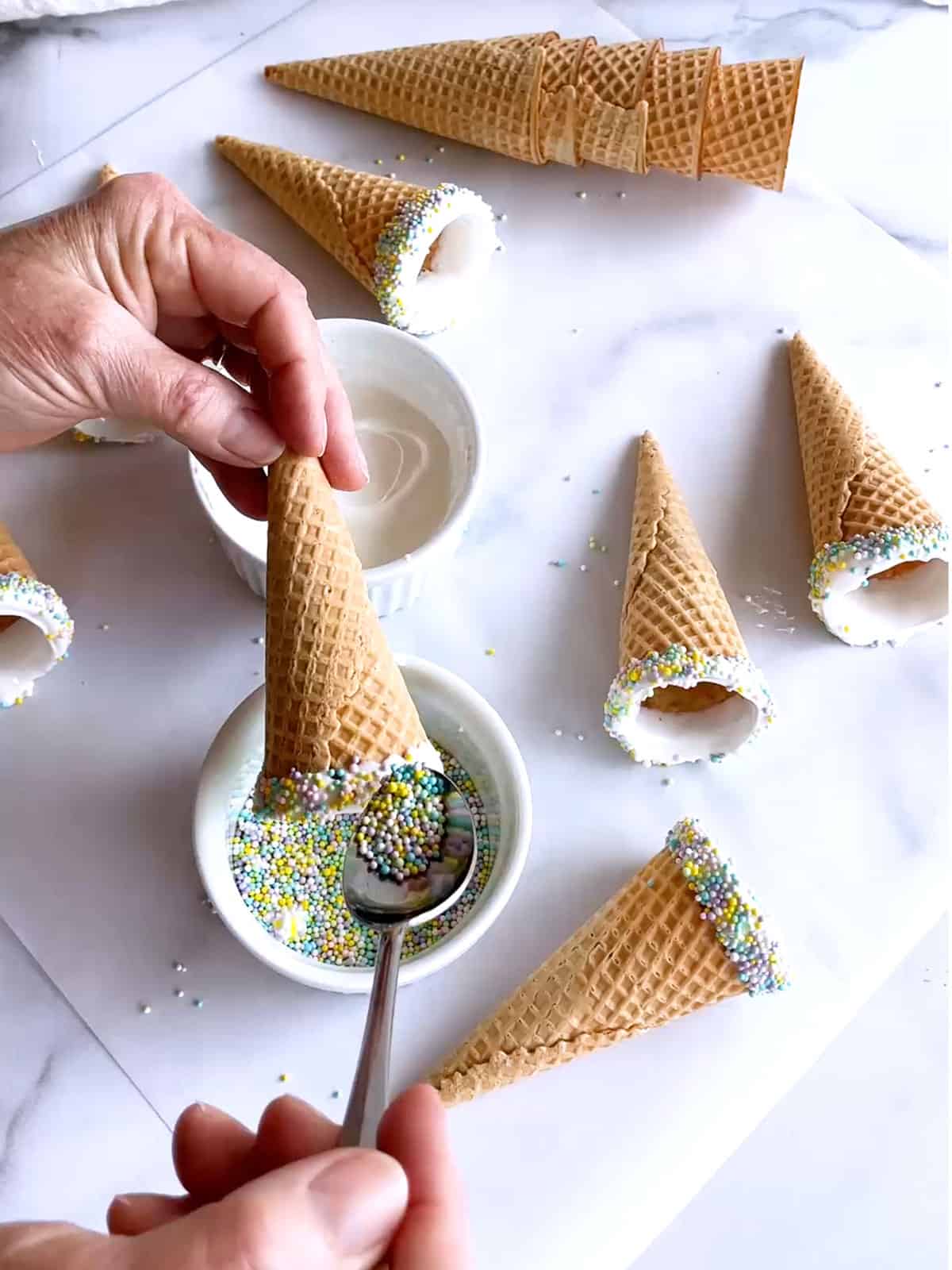 Adding sprinkles to the cones dipped in melted candy melts.