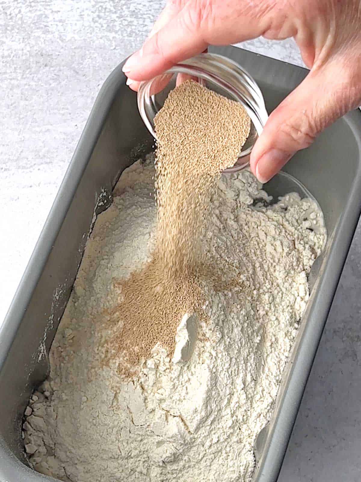 Adding yeast to bread machine with other ingredients.