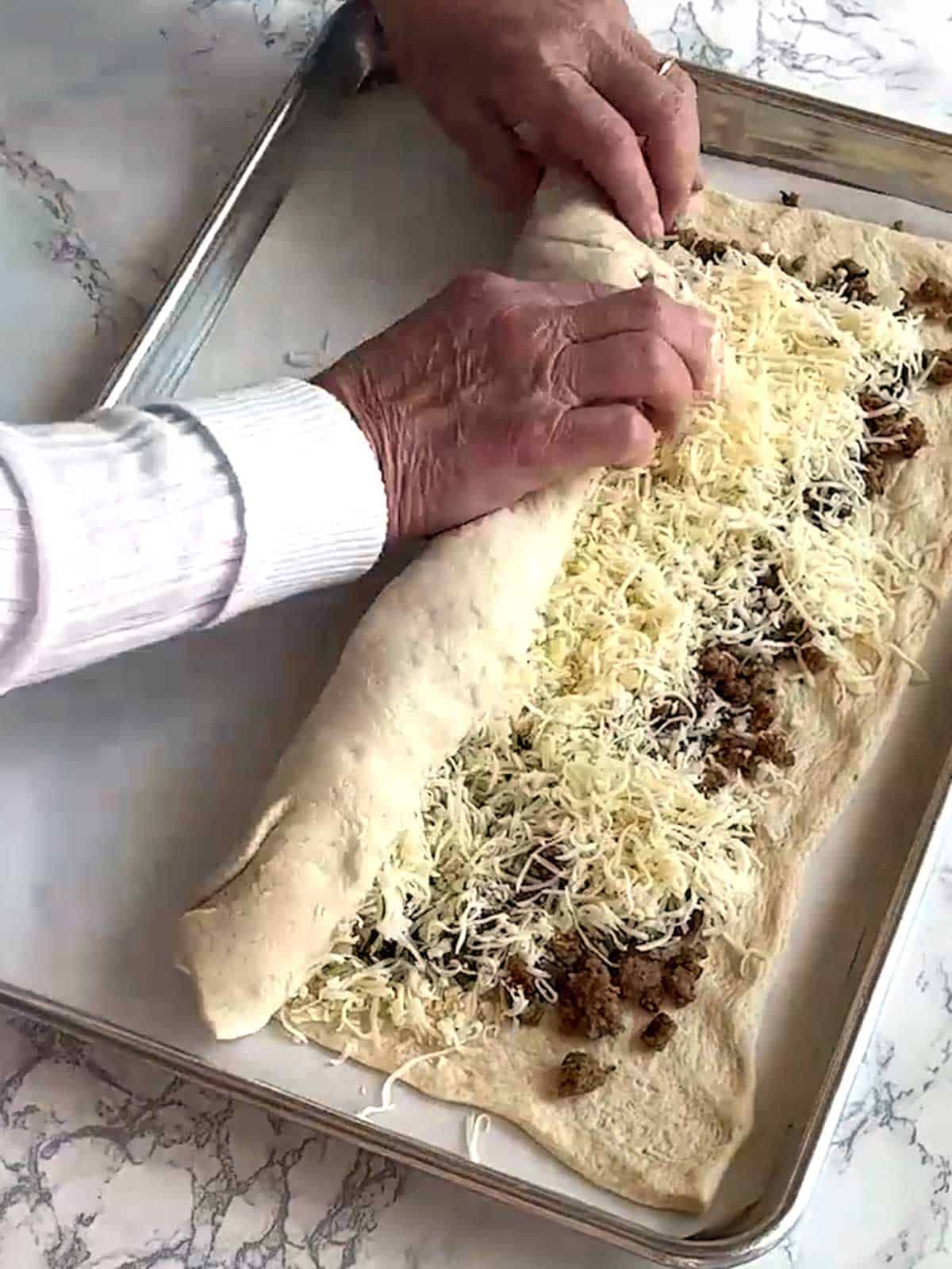 Rolling the sausage bread into a log.