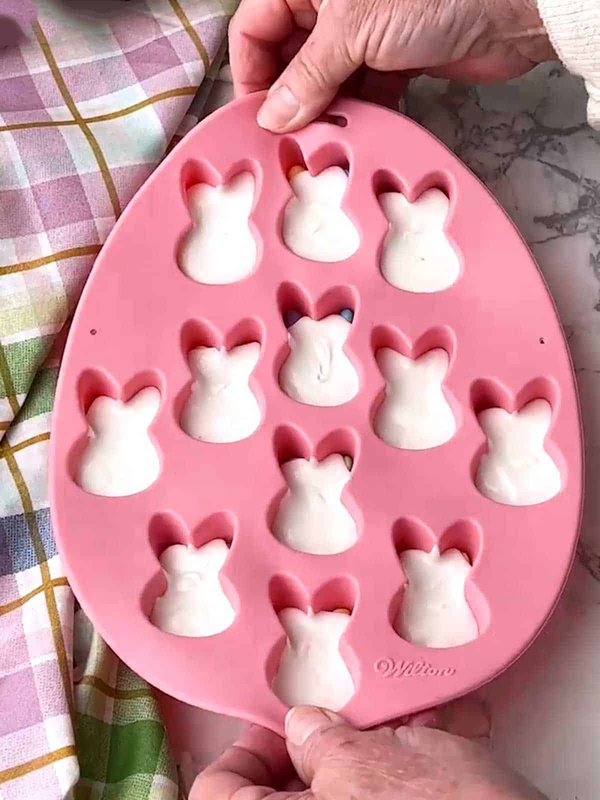 Tapping the bunny pan to distribute the melted candy melts.