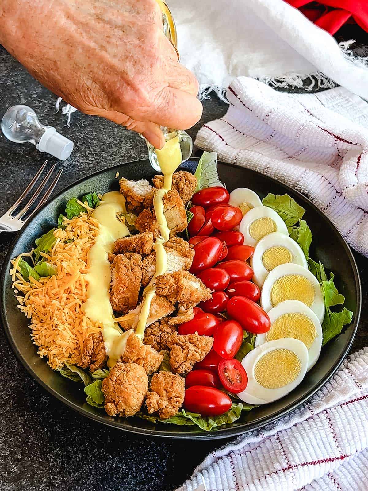 Pouring honey mustard dressing on the Southern Fried Chicken Salad.