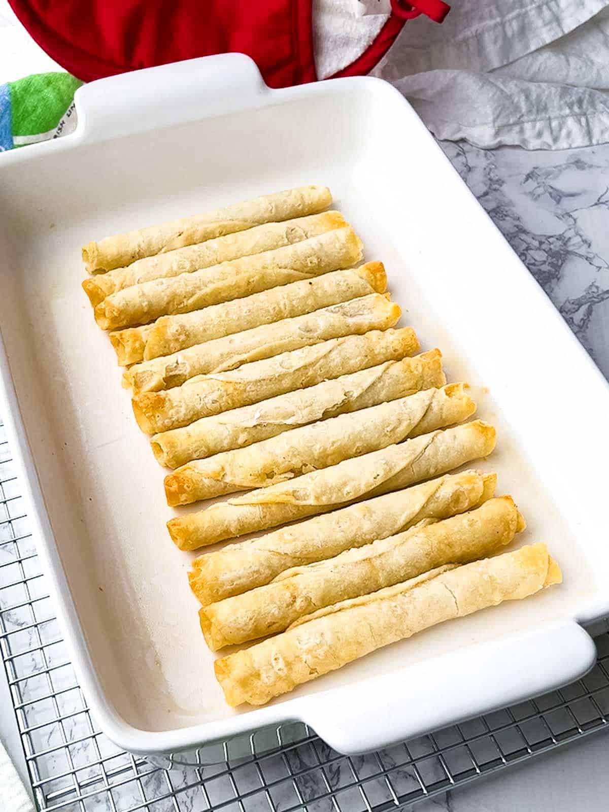 Browned taquitos in baking dish.