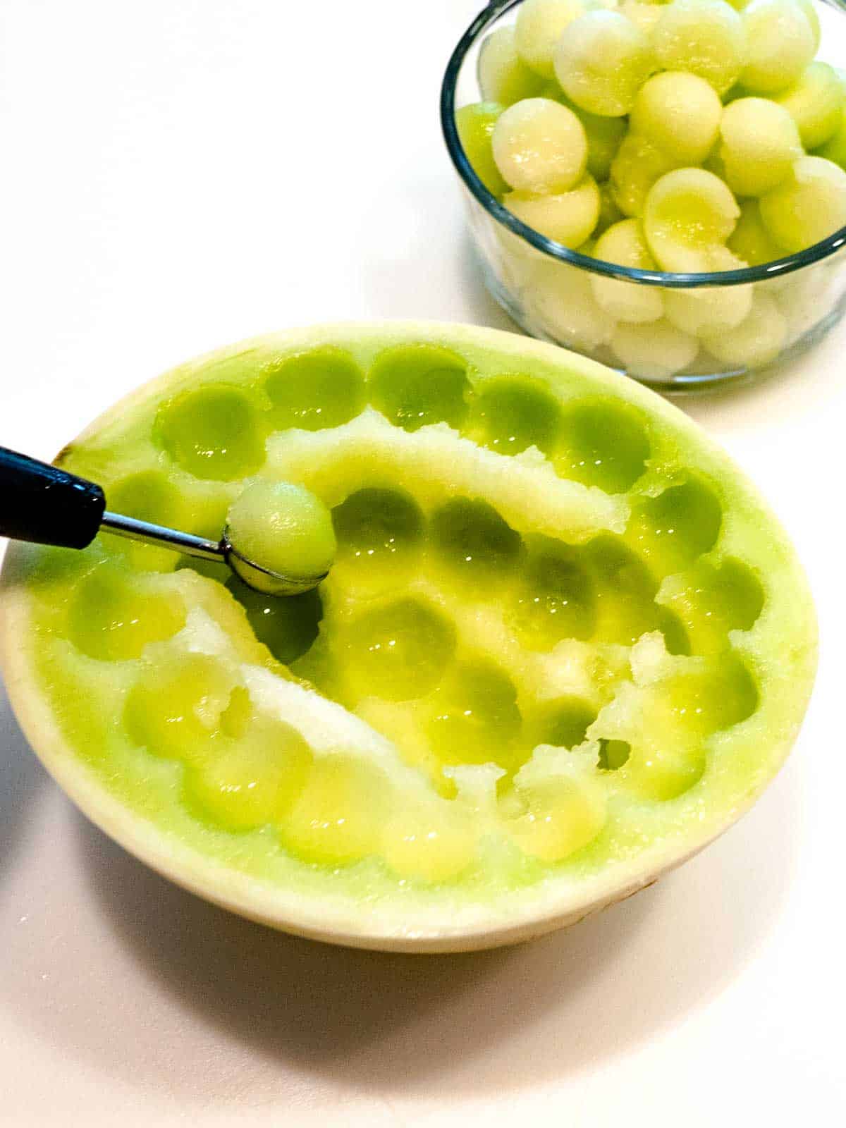 Scooping balls of honeydew melon.