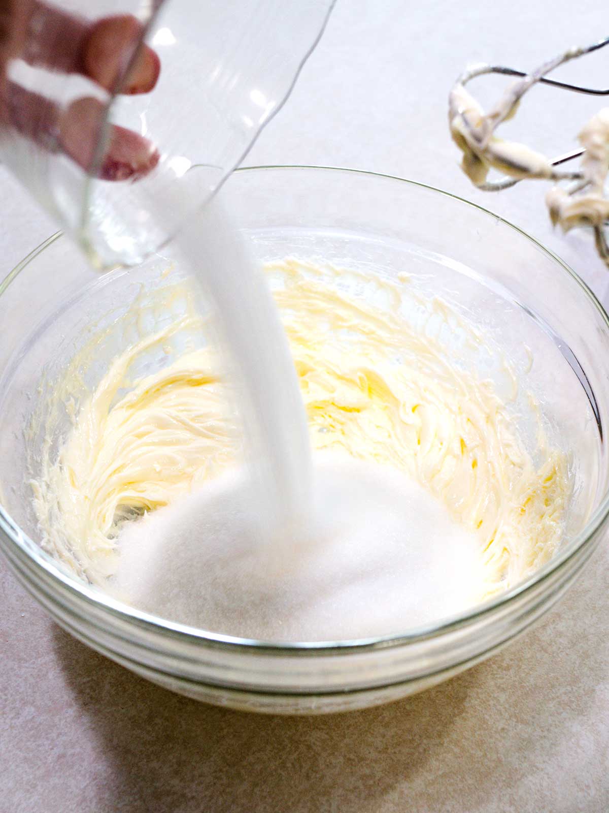 Adding sugar to butter that has been beaten.