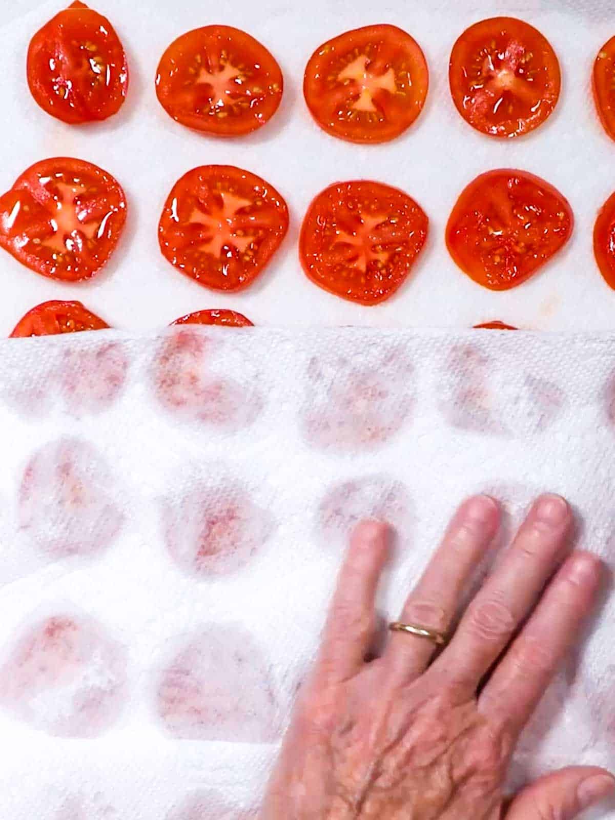 Blotting tomatoes with paper towel.