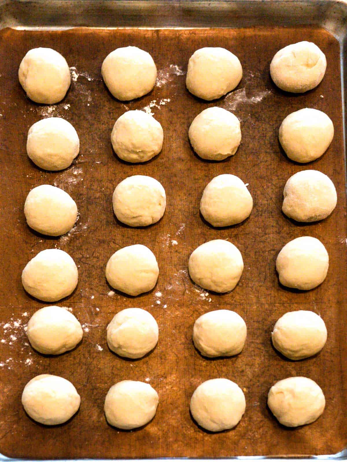 Dough balls on parchment lined baking sheet ready to rise.