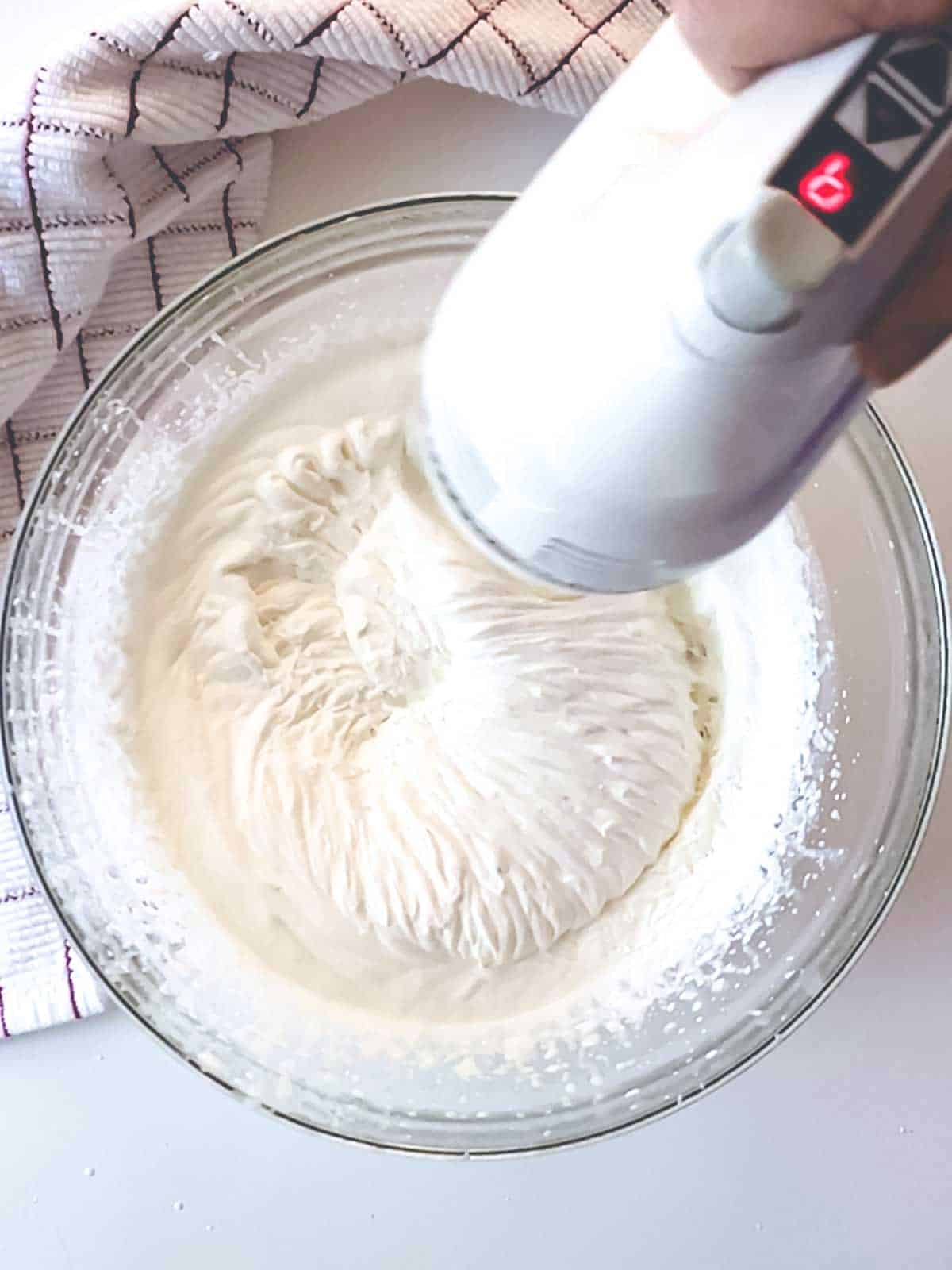 Beating heavy cream with electric mixer.