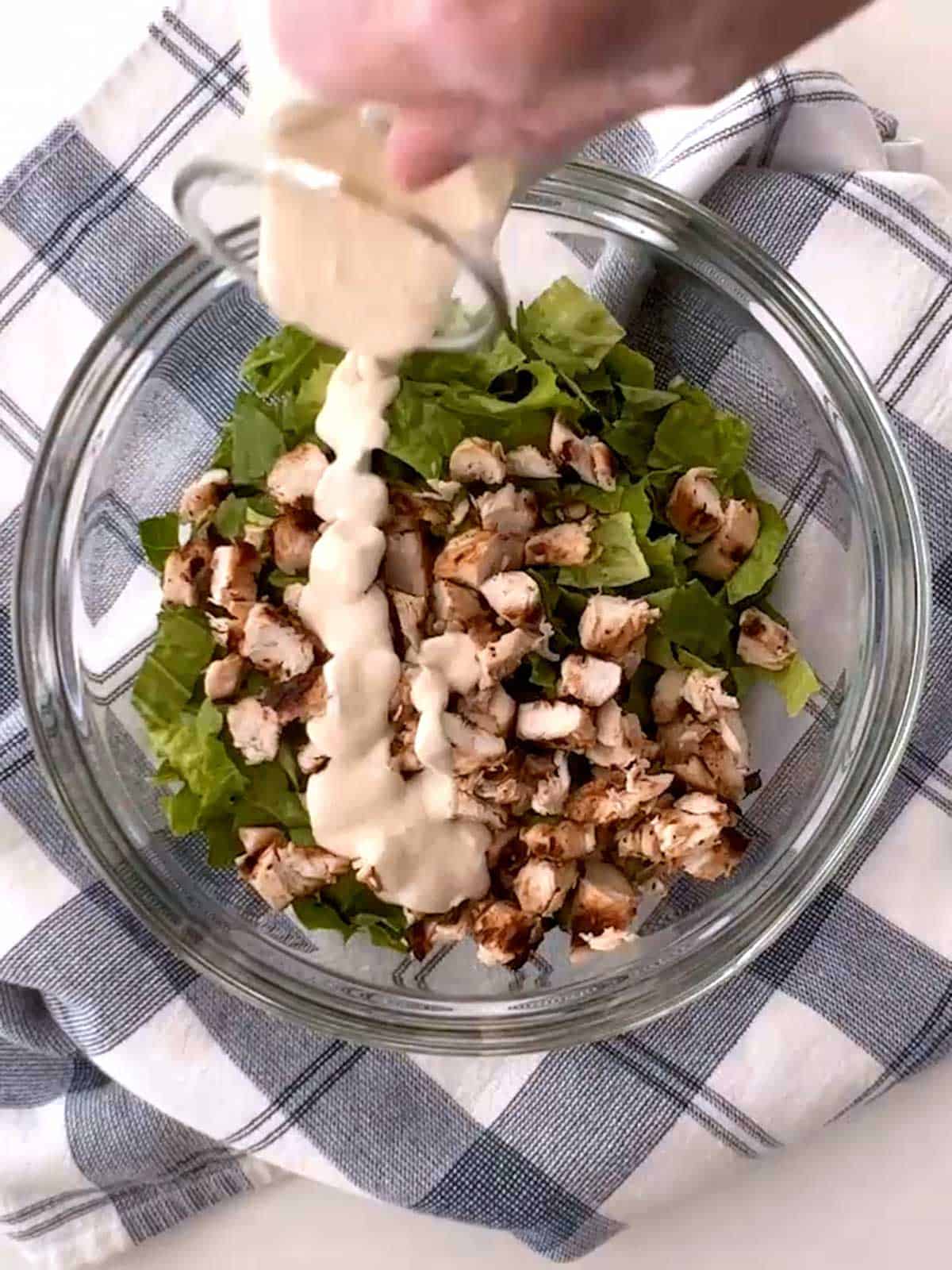 Adding dressing to Romaine lettuce and chicken.