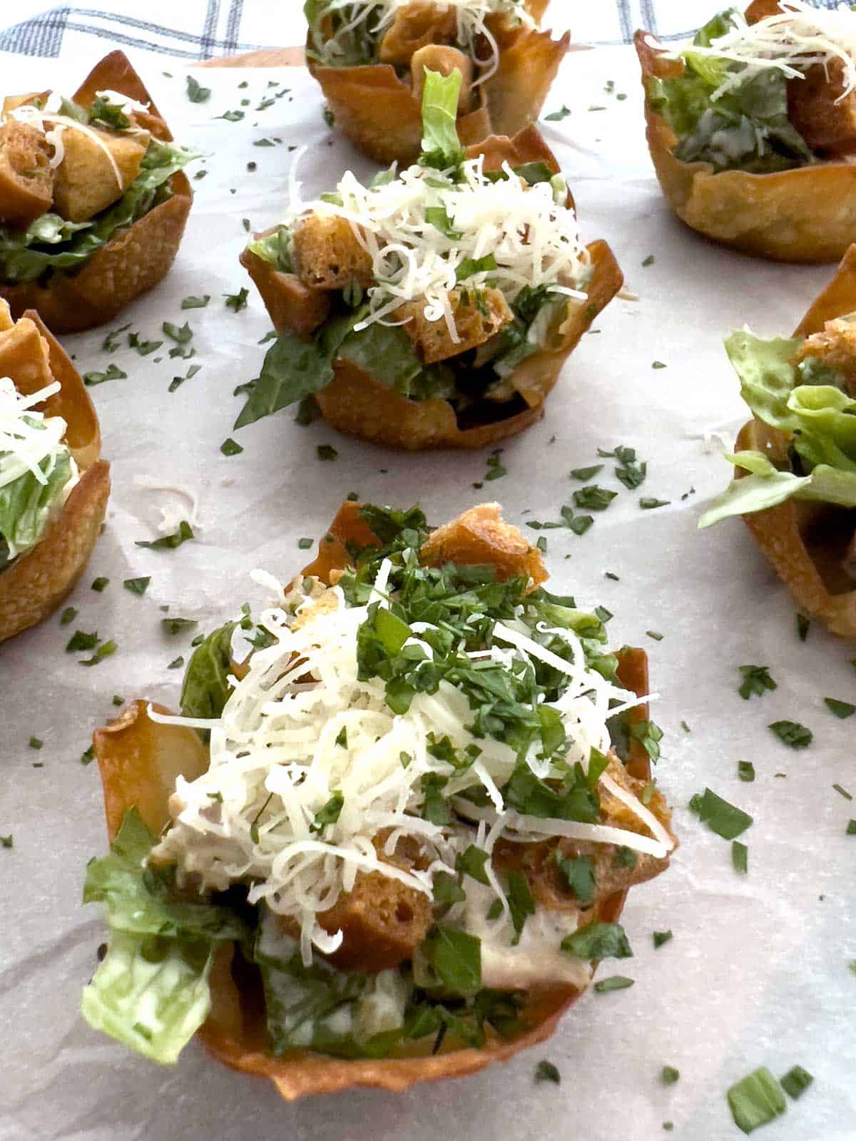Chicken Caesar salad cups topped with croutons and parmesan cheese.