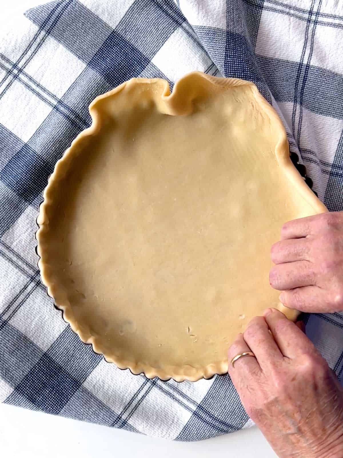 Pressing the pastry in a tart pan with removable bottom.