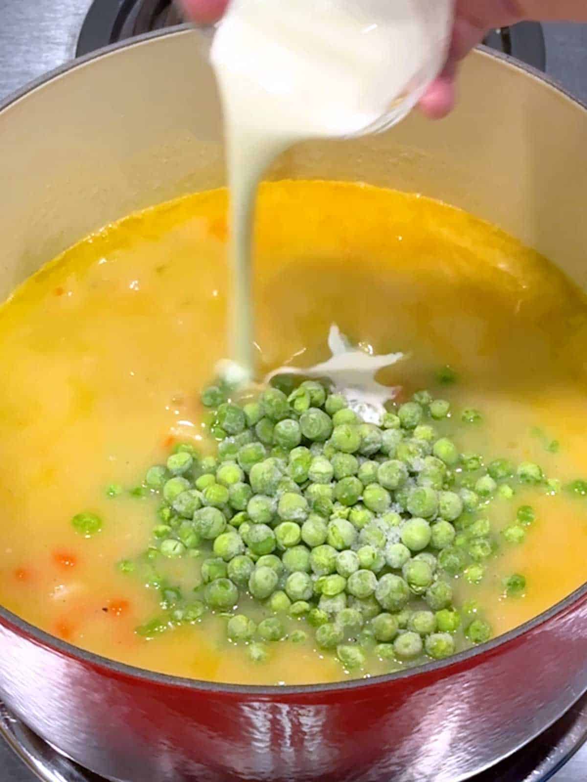 Adding frozen green peas and cream to the stew.