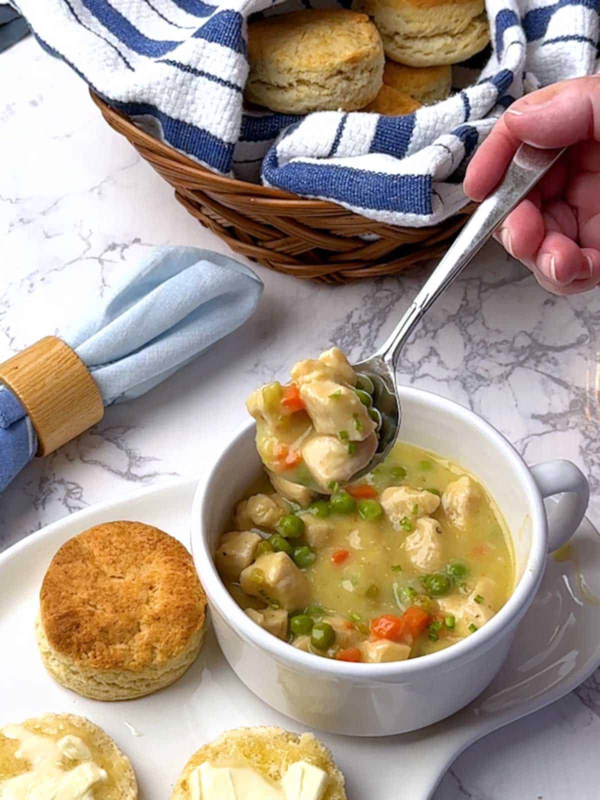 Eating the chicken stew with vegetables with biscuits on the side.