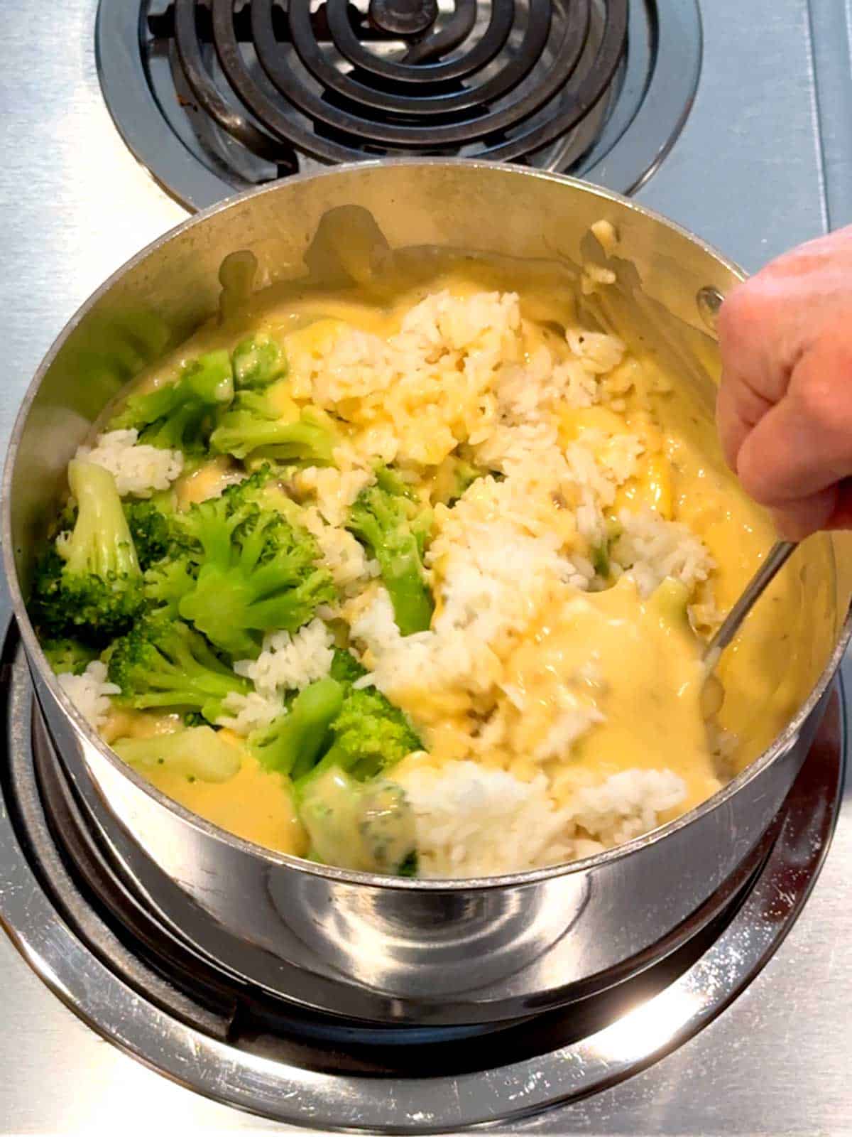 Stirring broccoli and rice in the cheese sauce.