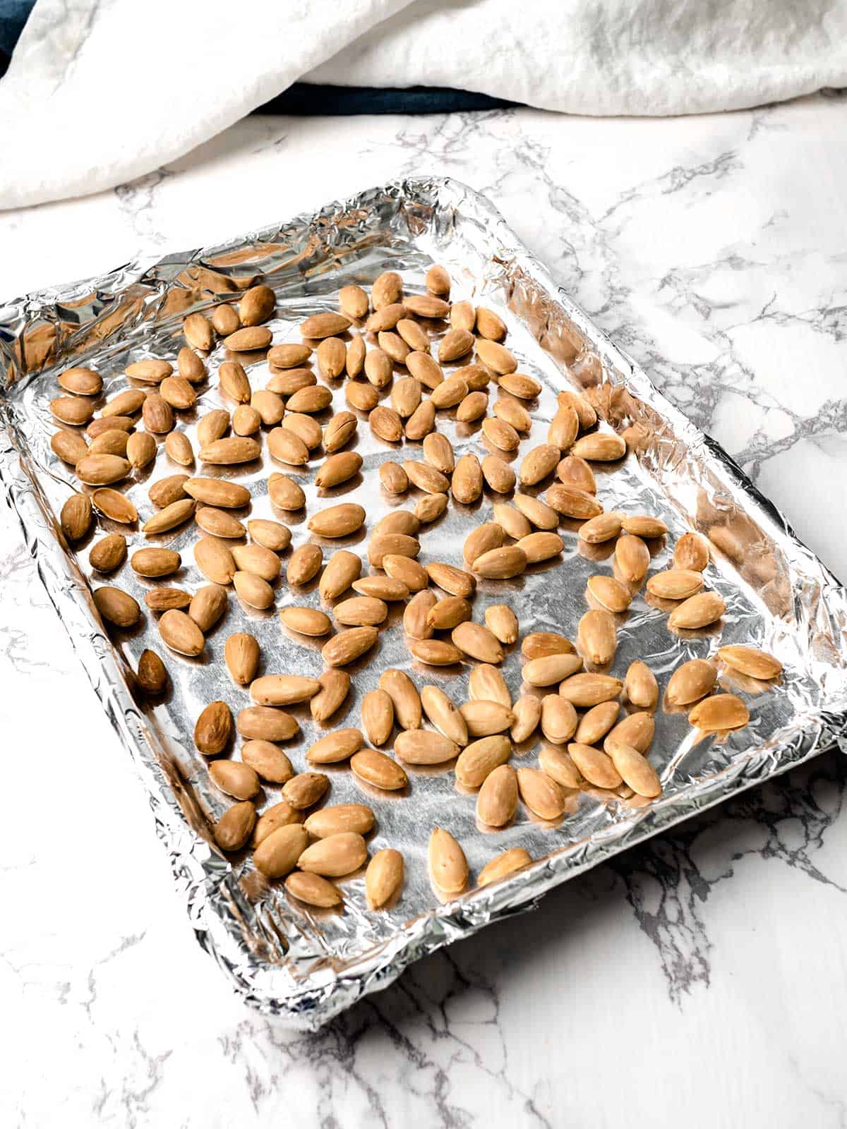 Toasted almonds on an aluminum foil lined baking sheet.