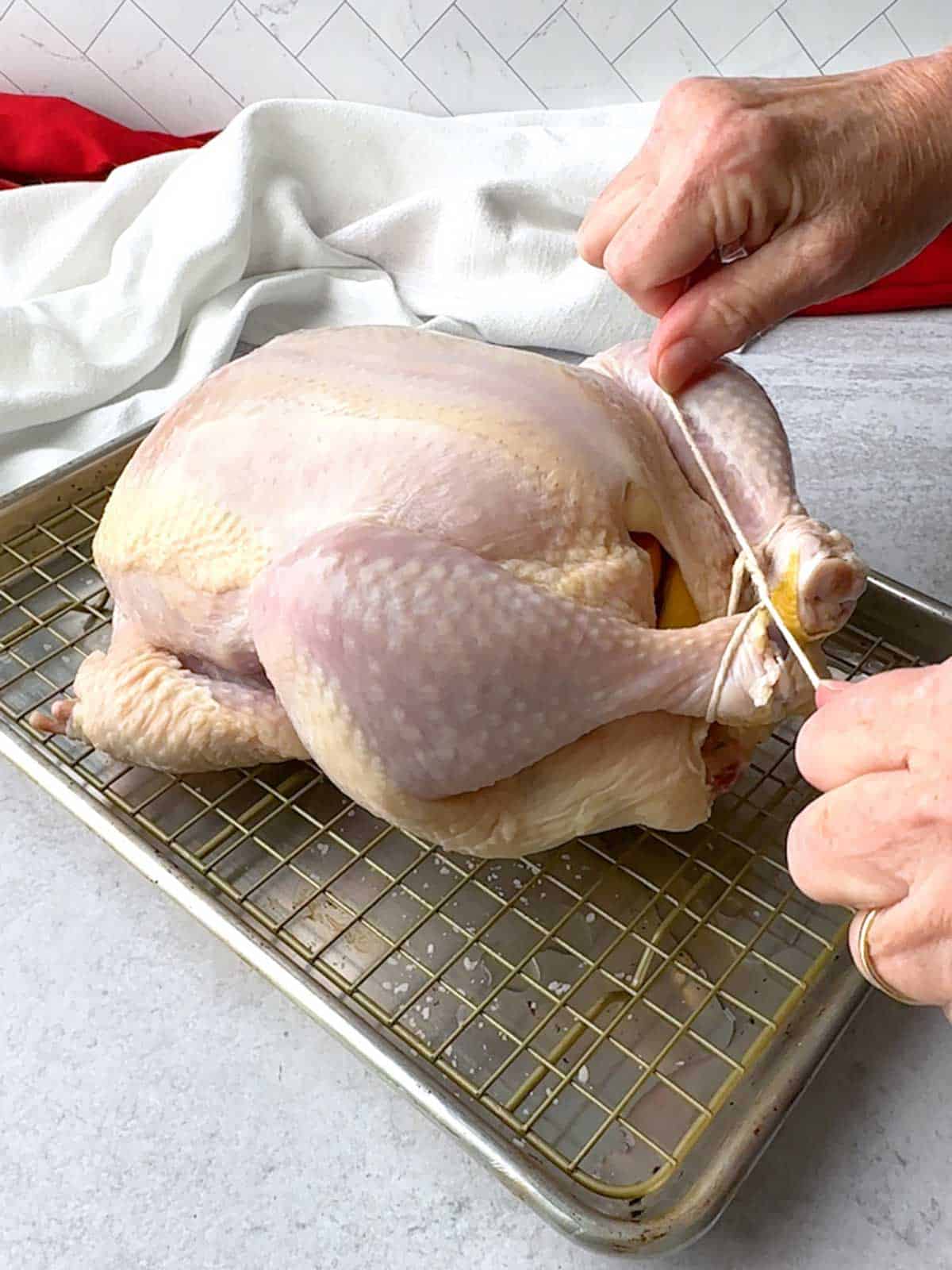 Tying the chicken legs together with kitchen twine.