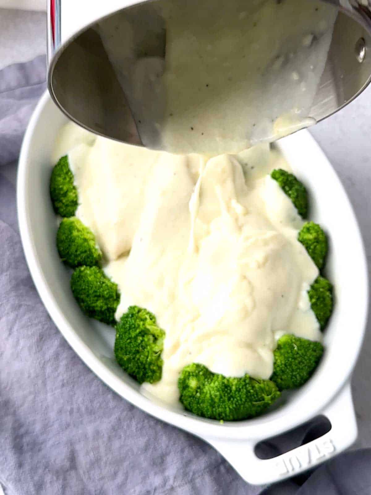 Pouring the white sauce over the chicken.