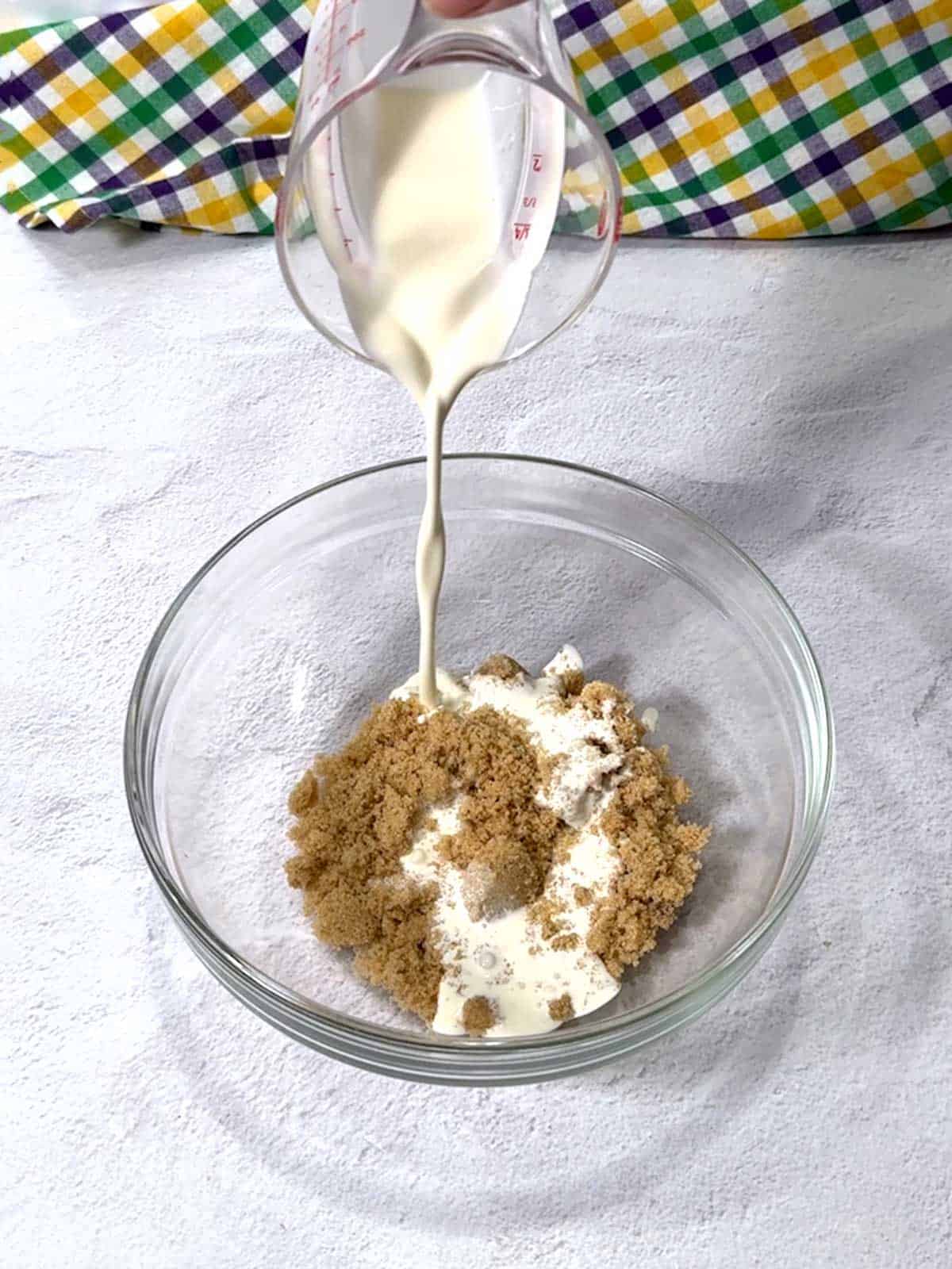 Adding cream to the brown sugar in a bowl.