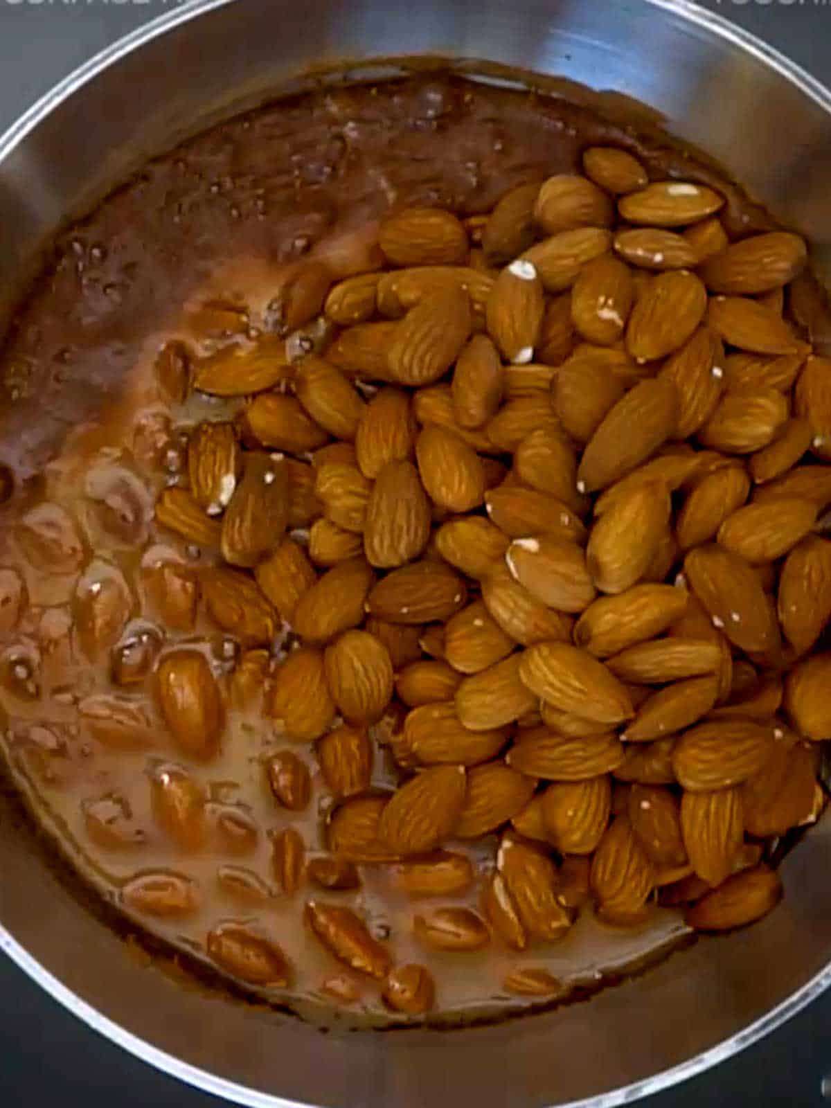 Almonds added to syrup in pan.