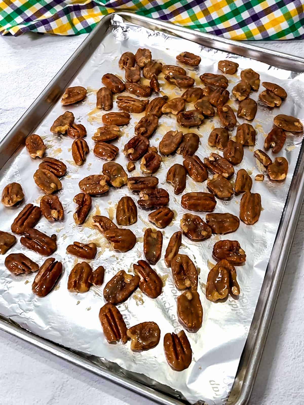 Pecans spread out on baking pan.