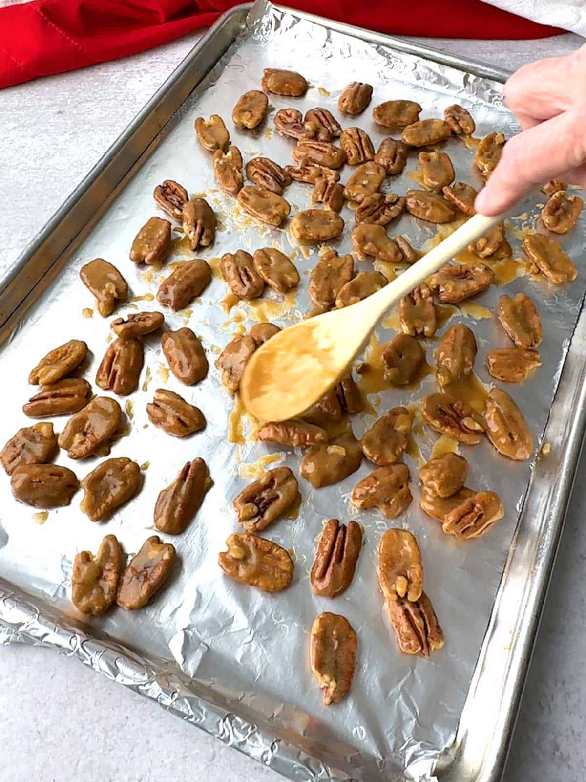 Spreading the coated pecans in a single layer on baking sheet.