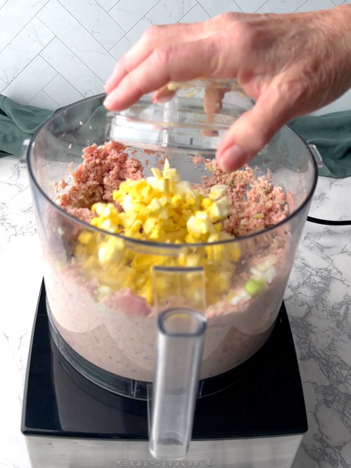 Adding chopped eggs to the food processor.