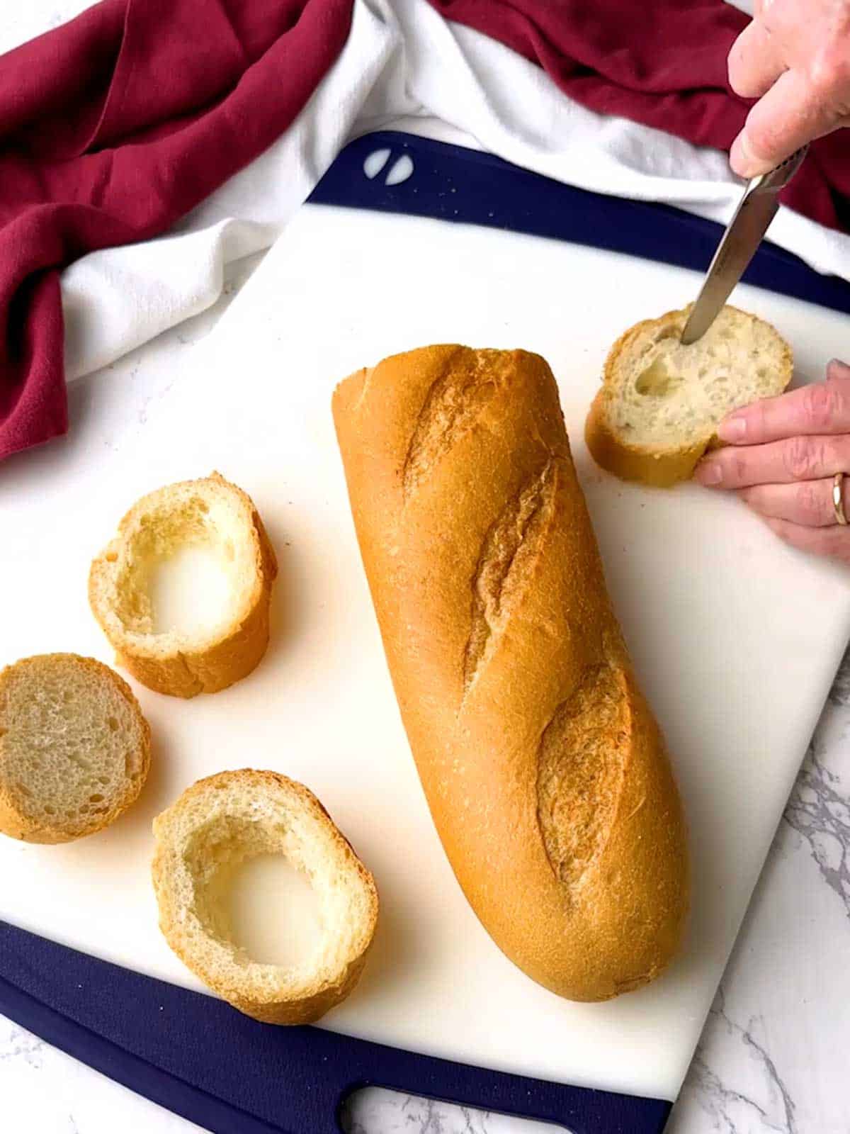 Cutting out the interior of a slice of French bread.