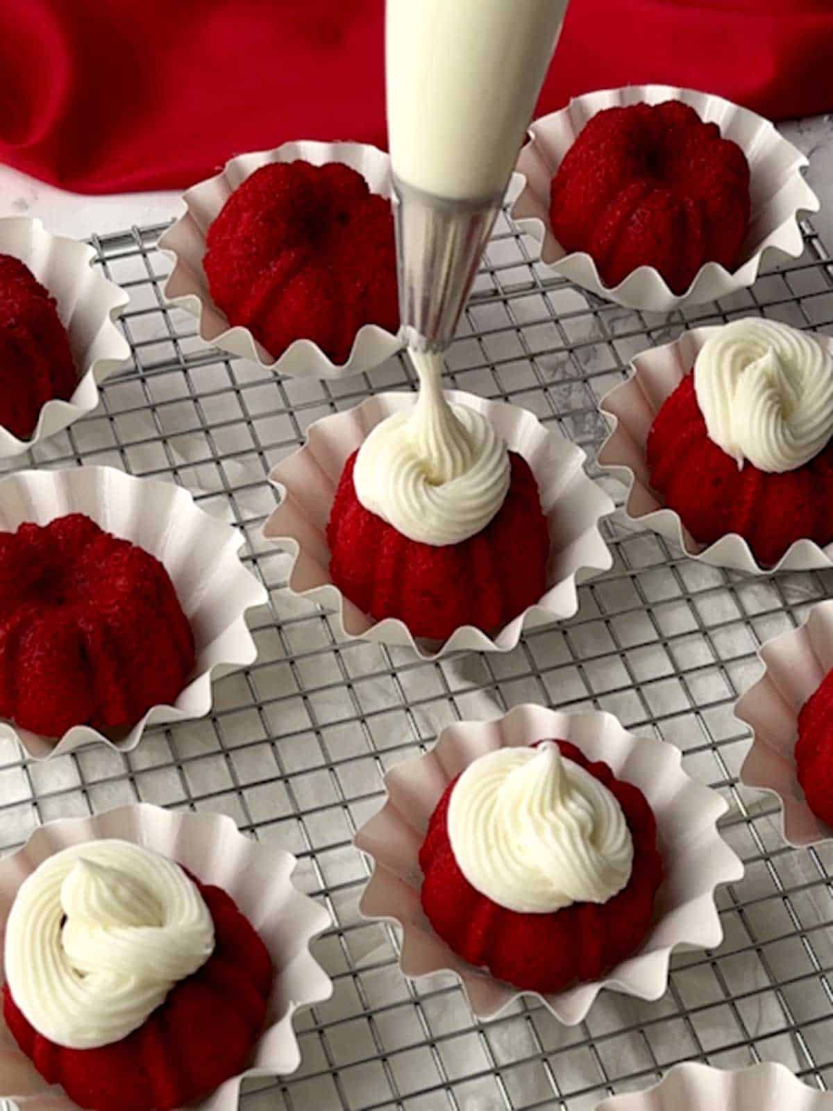 Piping frosting onto mini Bundt cakes.
