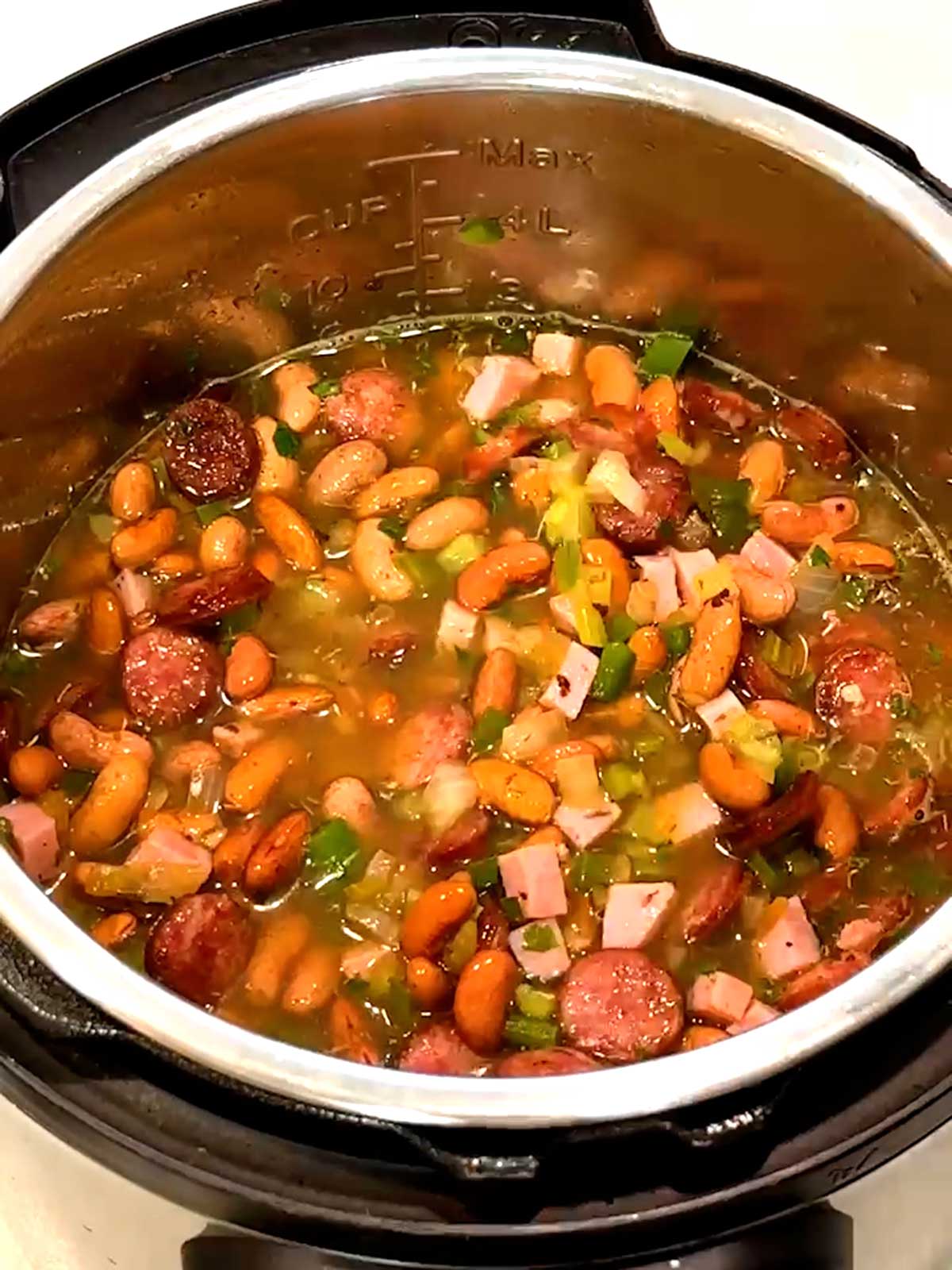 Drained kidney beans, water and cooked sausage stirred into mixture in Instant Pot.