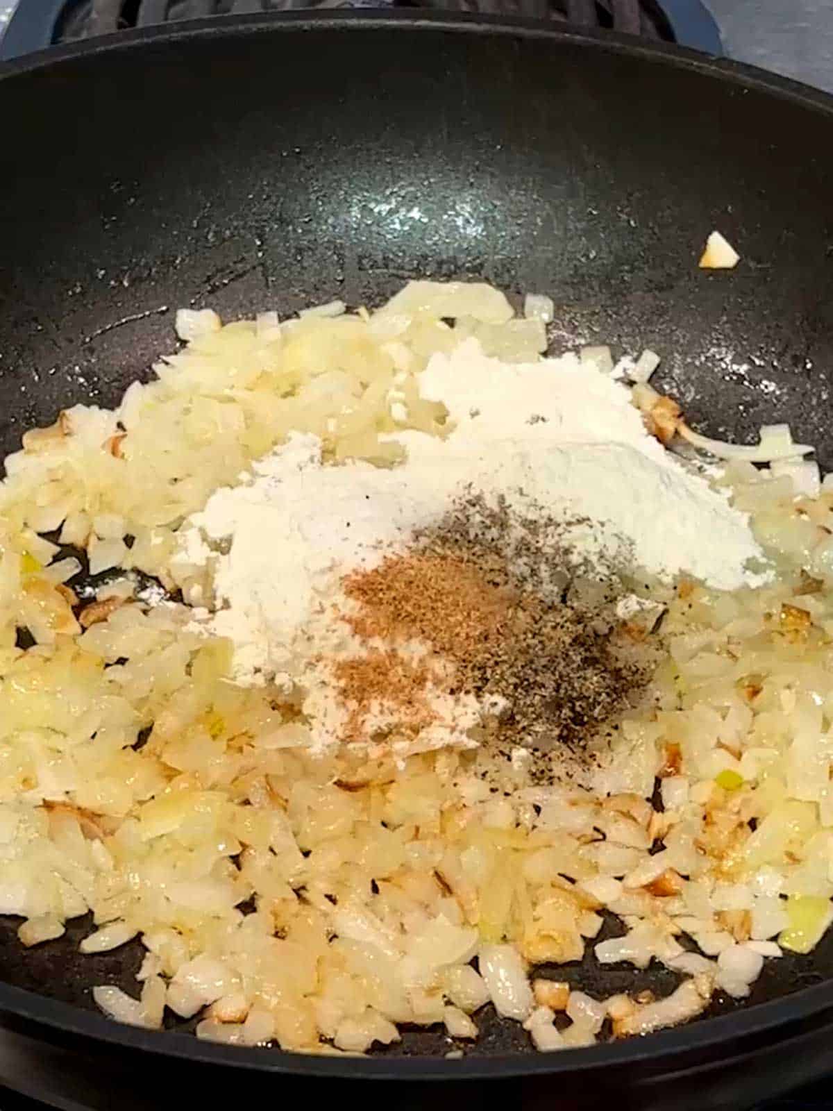 Flour, salt, pepper, and nutmeg added to the onions in the skillet.