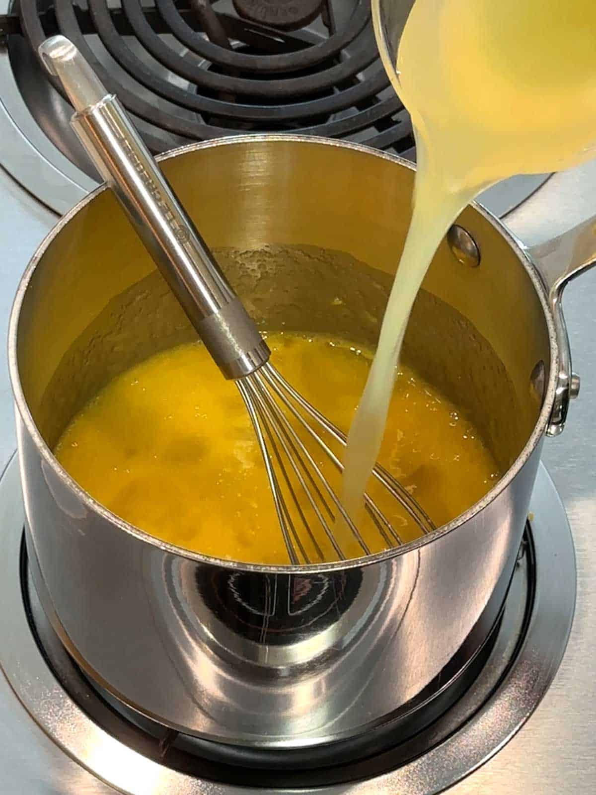 Adding lemon juice to the sugar, eggs and lemon zest in a saucepan.