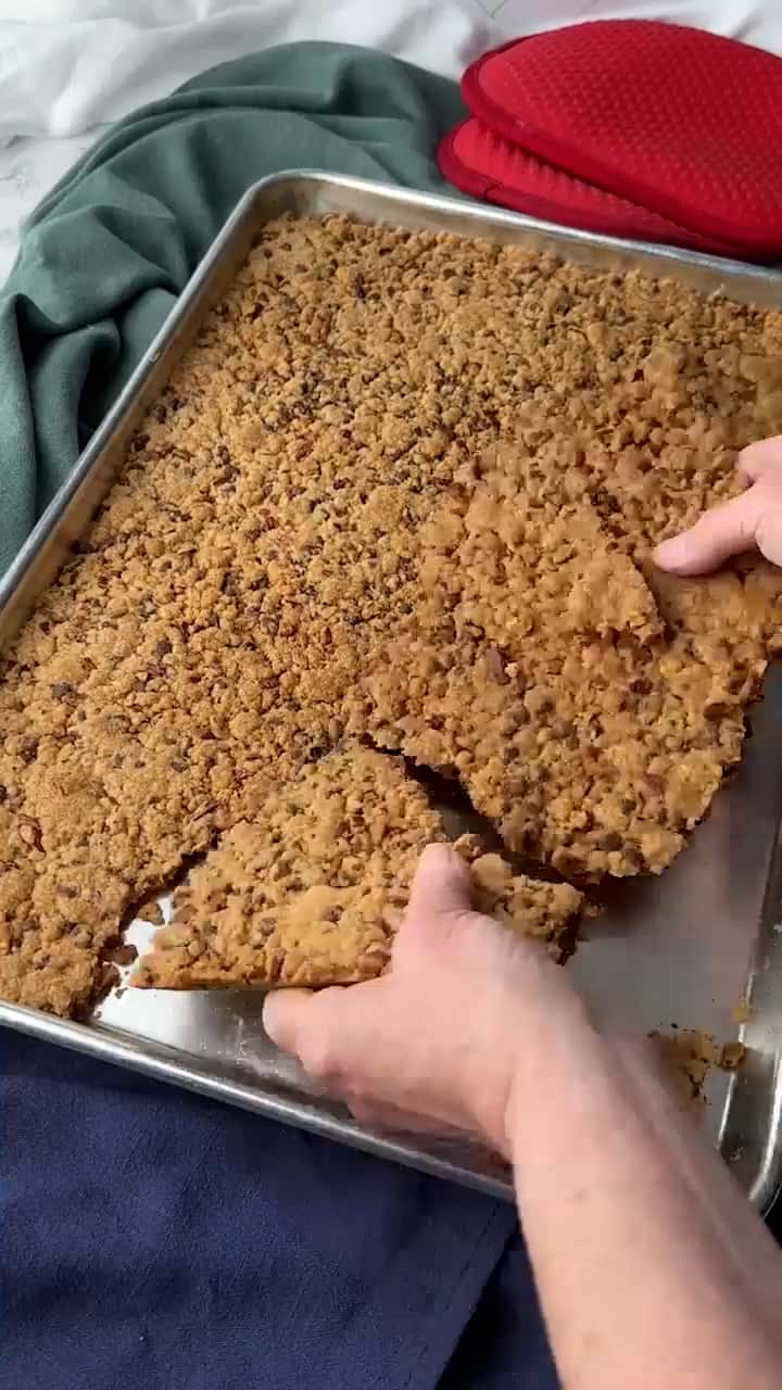 Breaking the cookie brittle into pieces to serve.