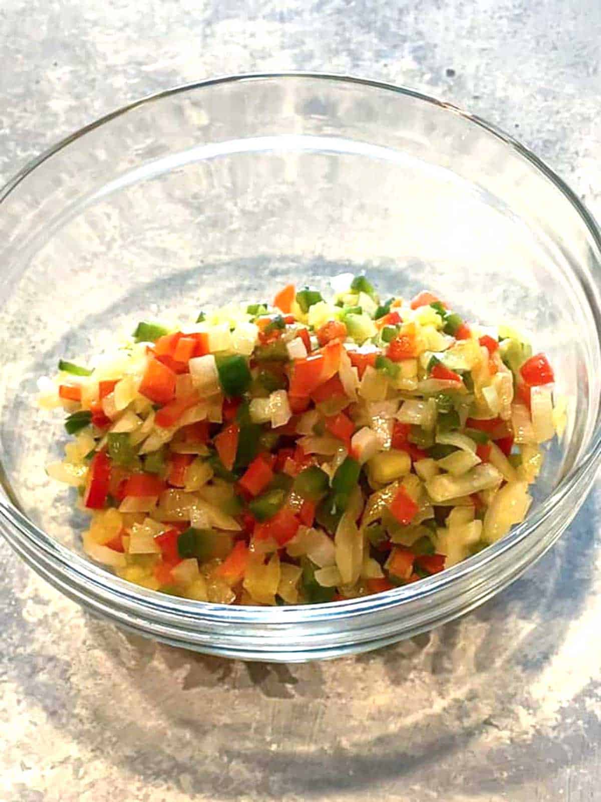 Cooked onions, red bell pepper, jalapeño peppers and garlic in a bowl,.