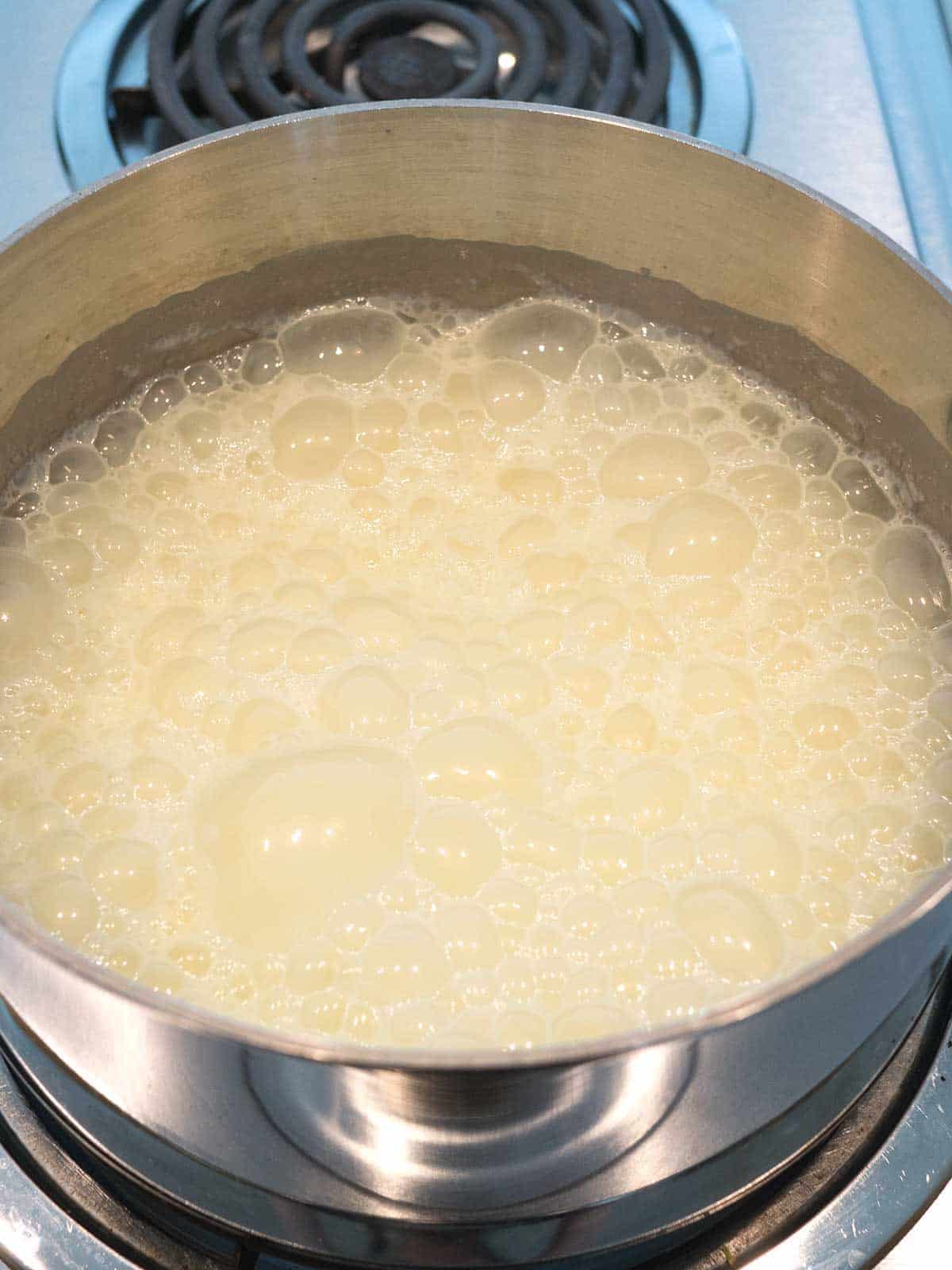 Boiling the cream, sugar and lemon zest in a heavy saucepan over medium heat.