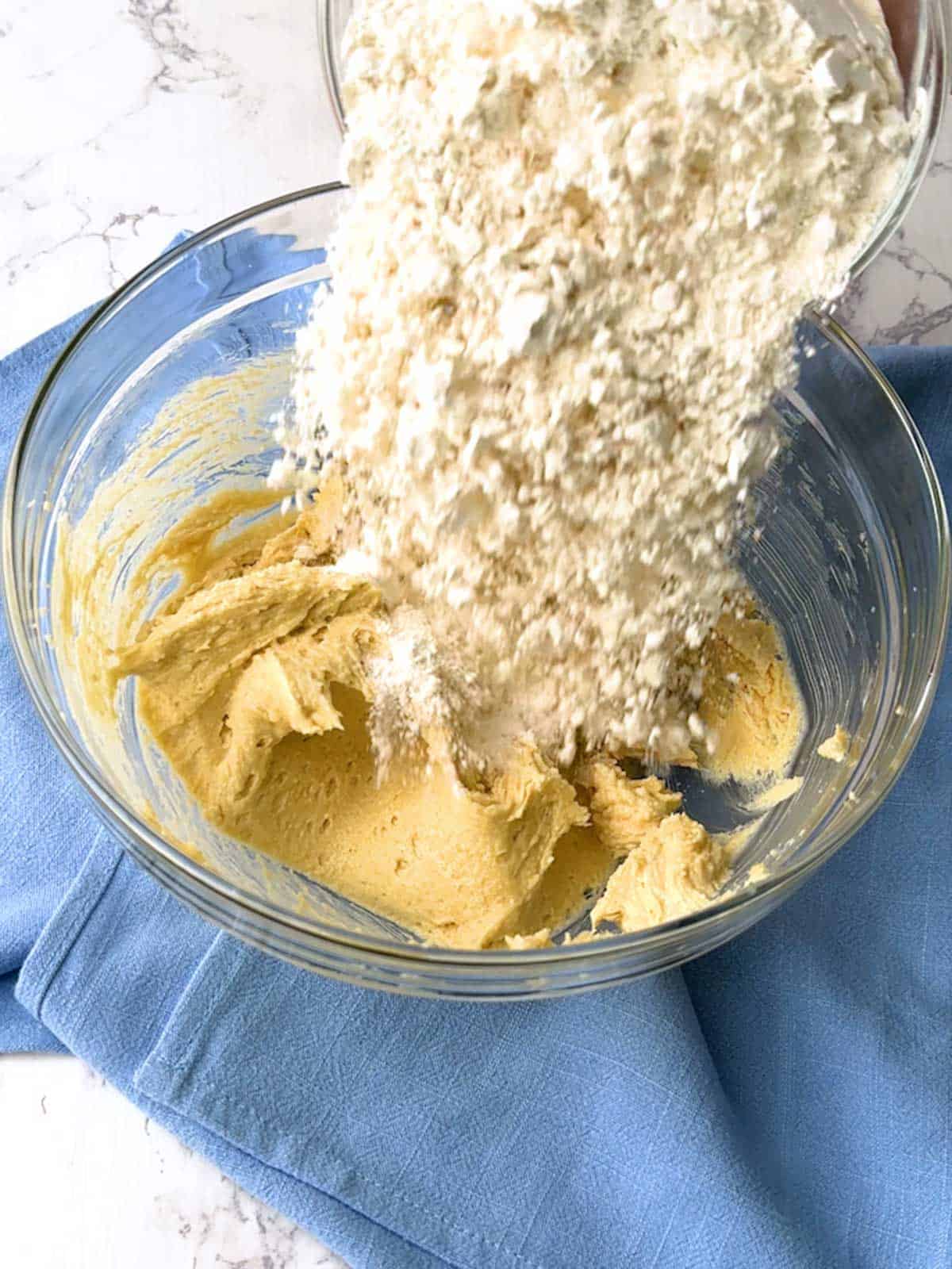 Adding flour to the butter/sugar mixture in a bowl.