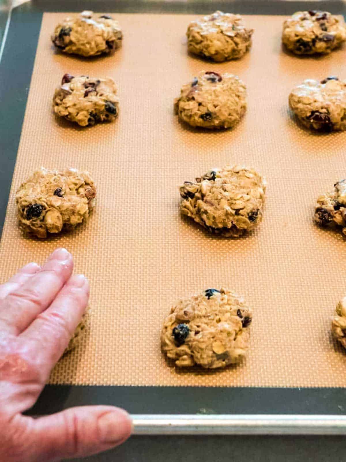 Flattening cookie dough with damp hand.