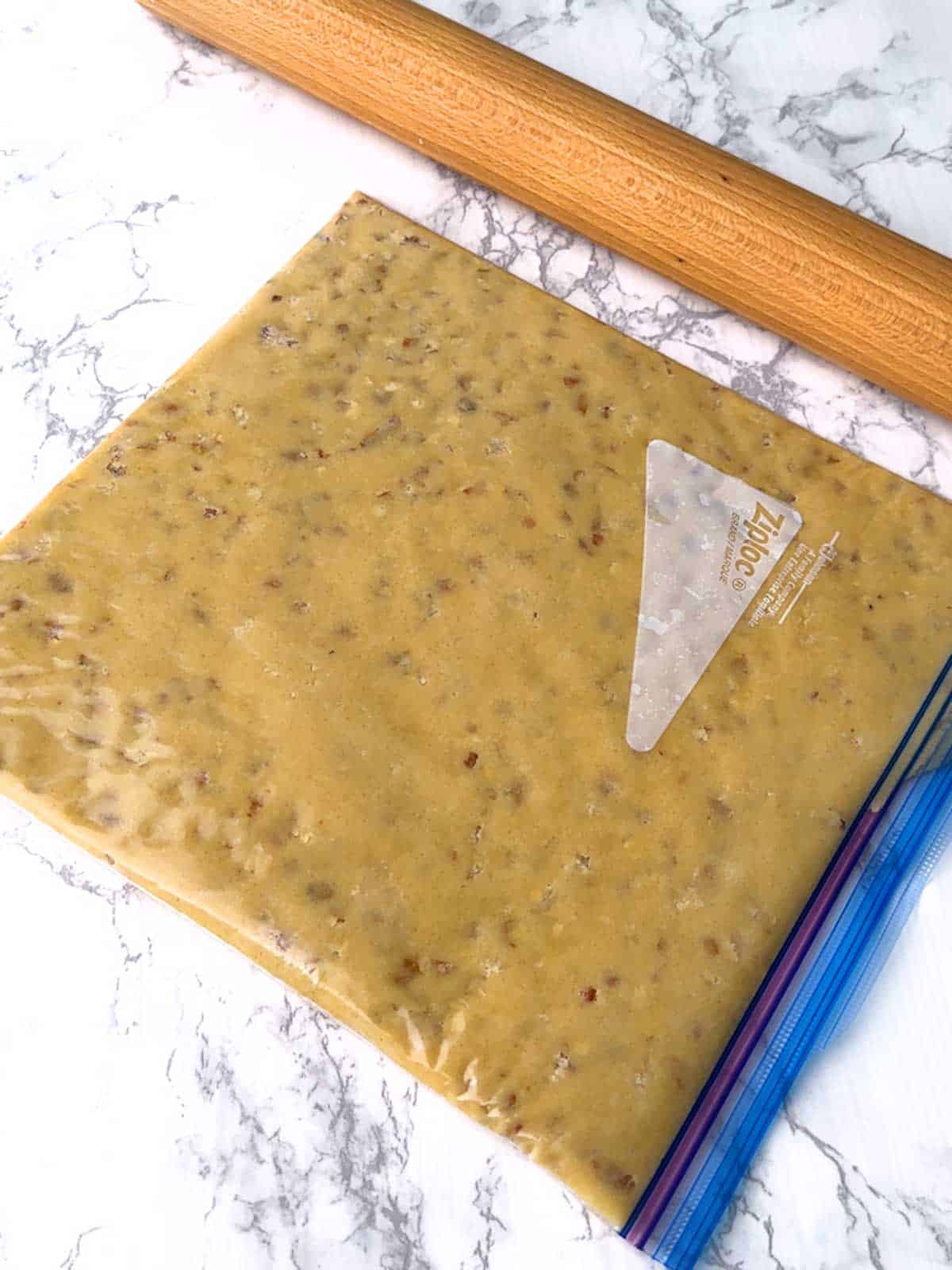 Cookie dough in a Ziploc bag with the rolling pin.