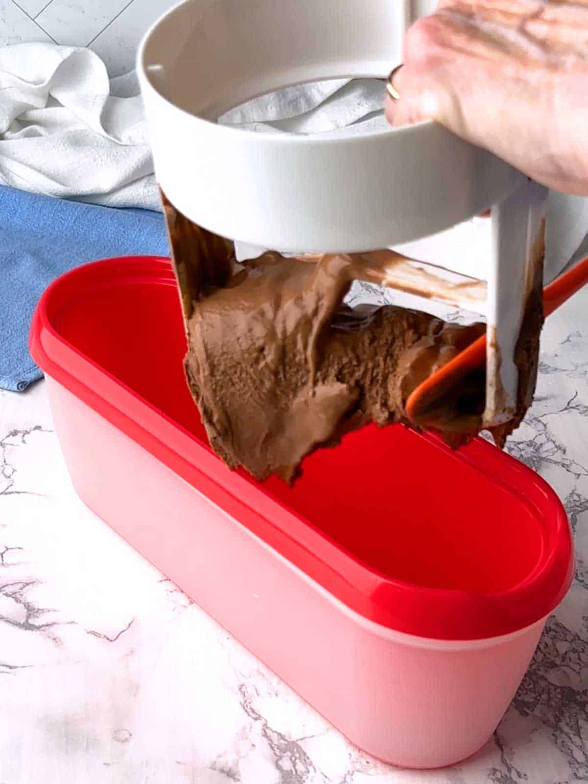 Adding frozen yogurt to the container for freezing.