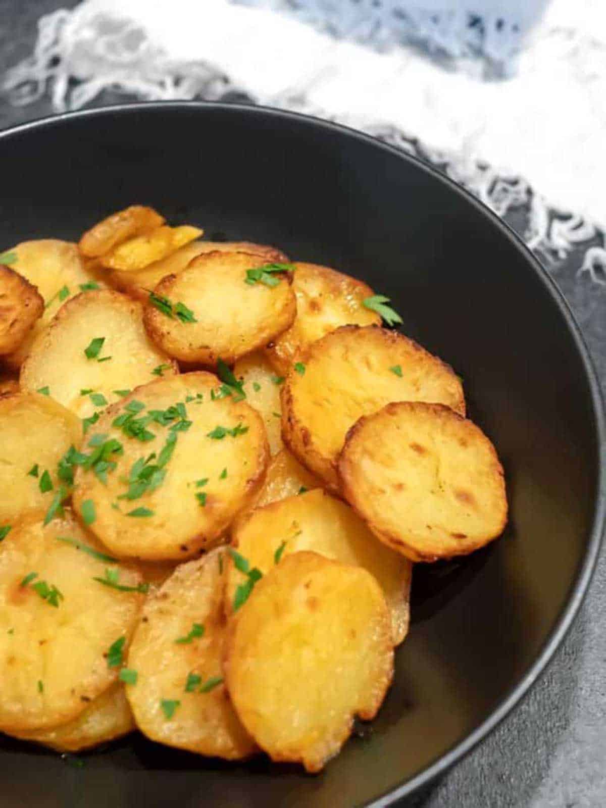 Oven-roasted potatoes in a black bowl.