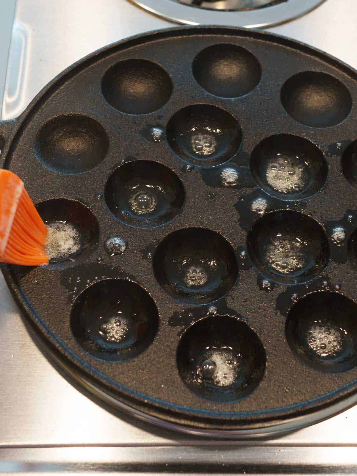 Brushing the Poffertjes pan with melted butter.