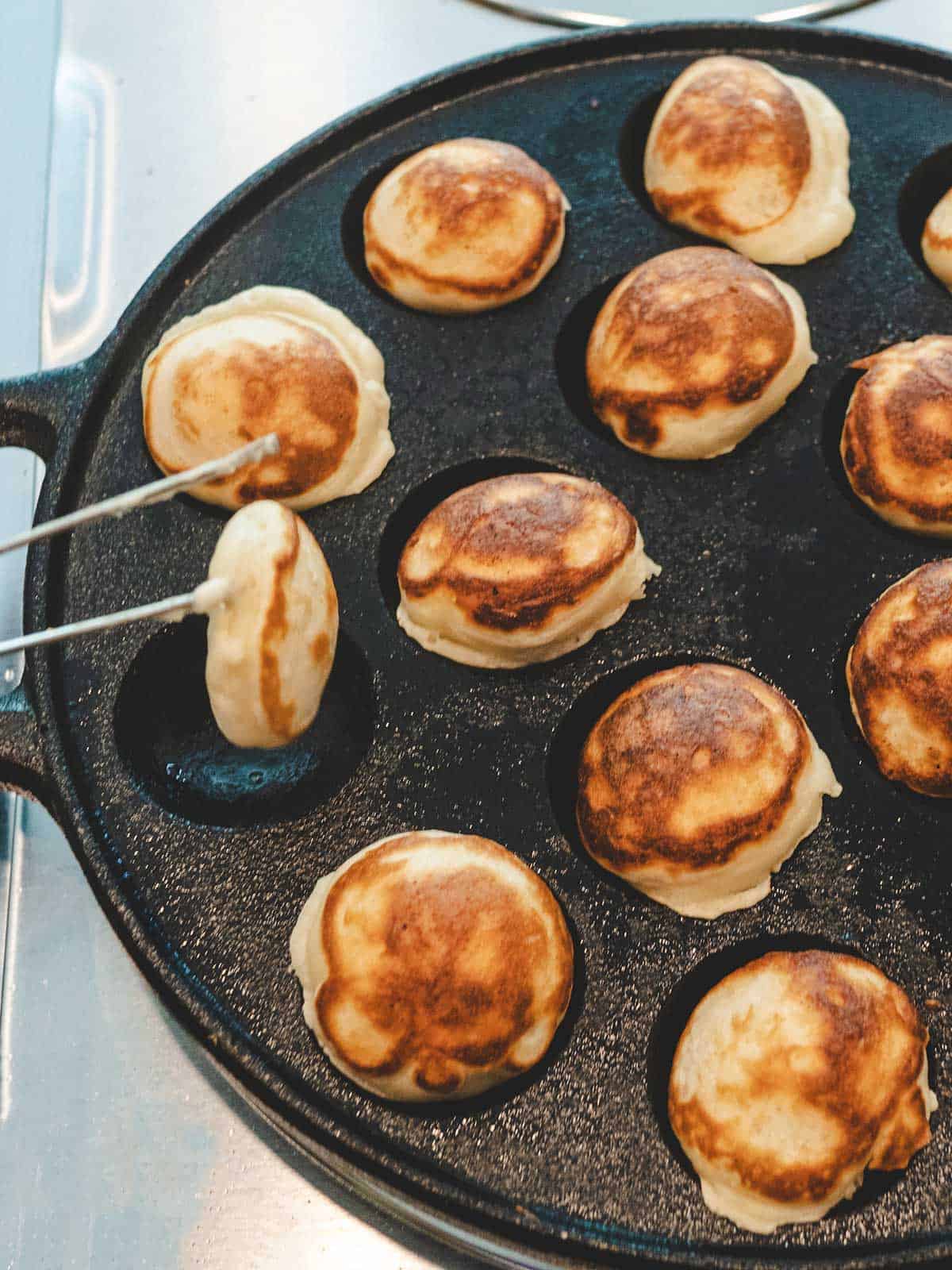 Flipping the Poffertjes to the other side to finish cooking.