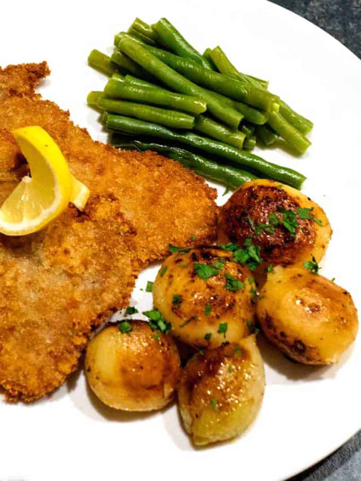 Potatoes and onions with schnitzel and green beans.