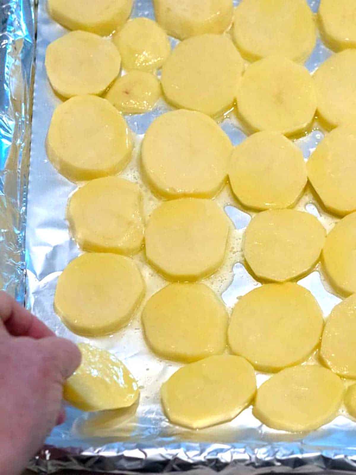 Potatoes coated in butter spread in a single layer on a baking sheet that was lined with nonstick aluminum foil.