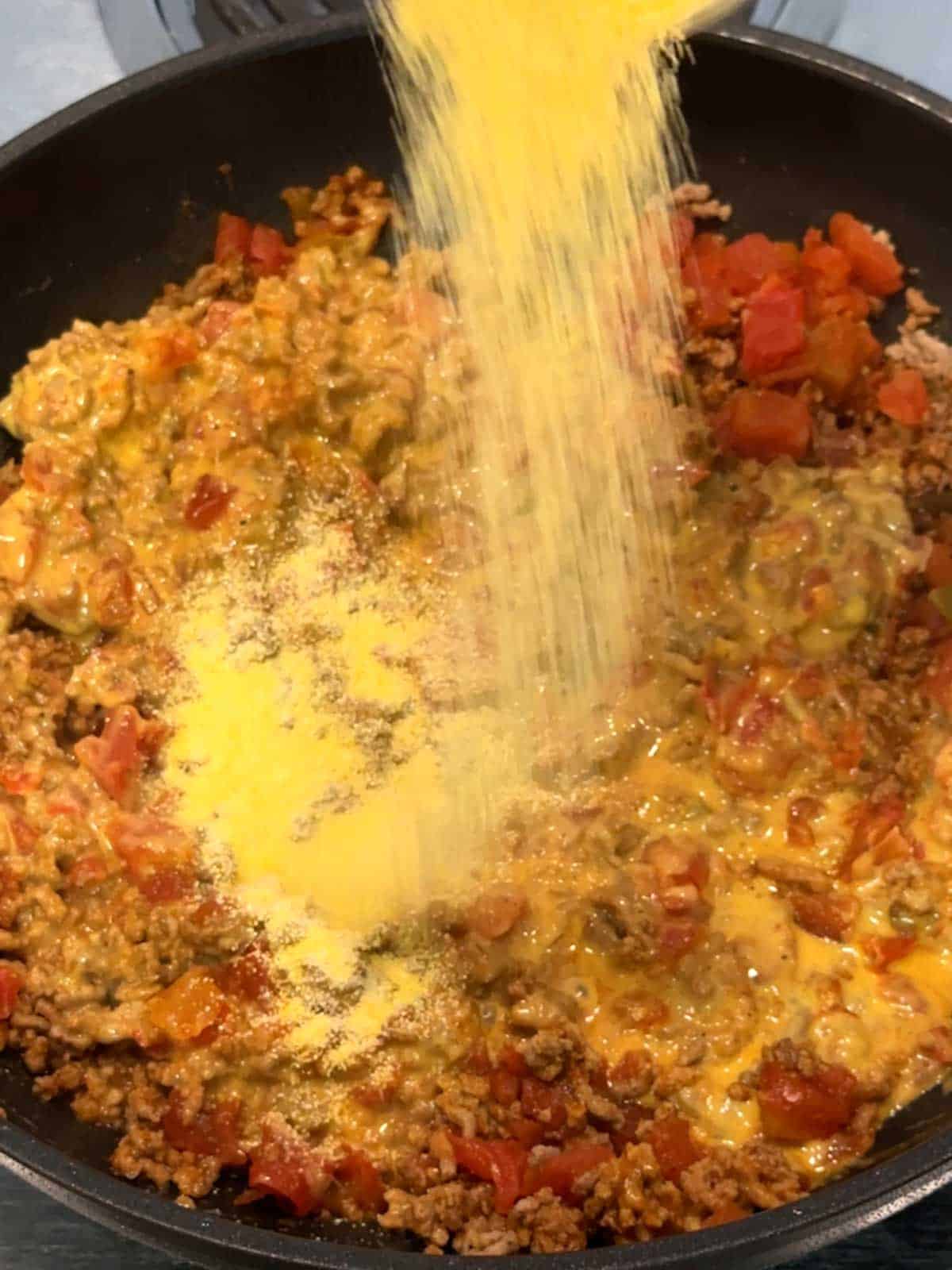 Adding cornmeal to the taco meat with Velveeta cheese.