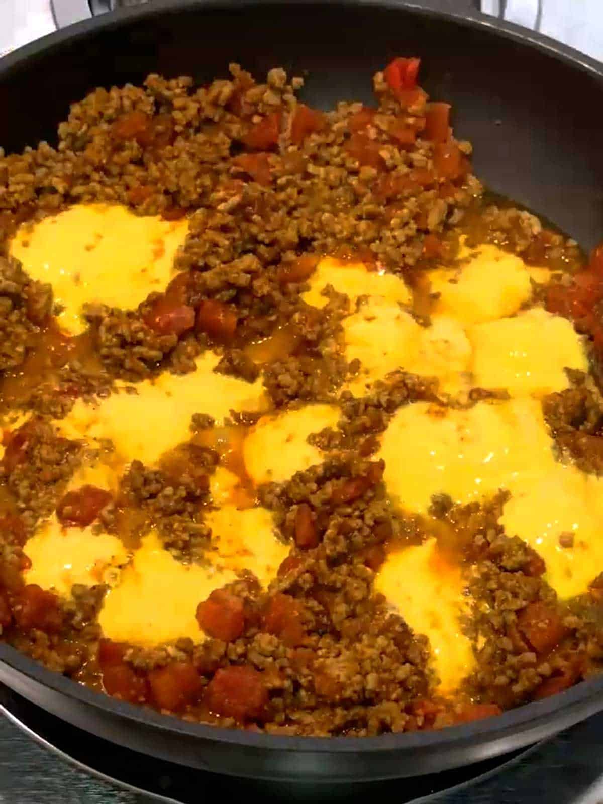 Melted velveeta cheese in skillet with the seasoned ground beef.